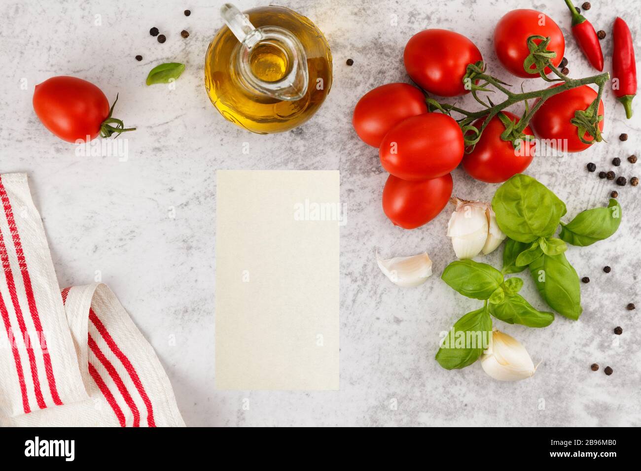 Pomodori freschi e colorati, basilico e olio d'oliva su tavola bianca. Vista dall'alto con spazio di copia Foto Stock