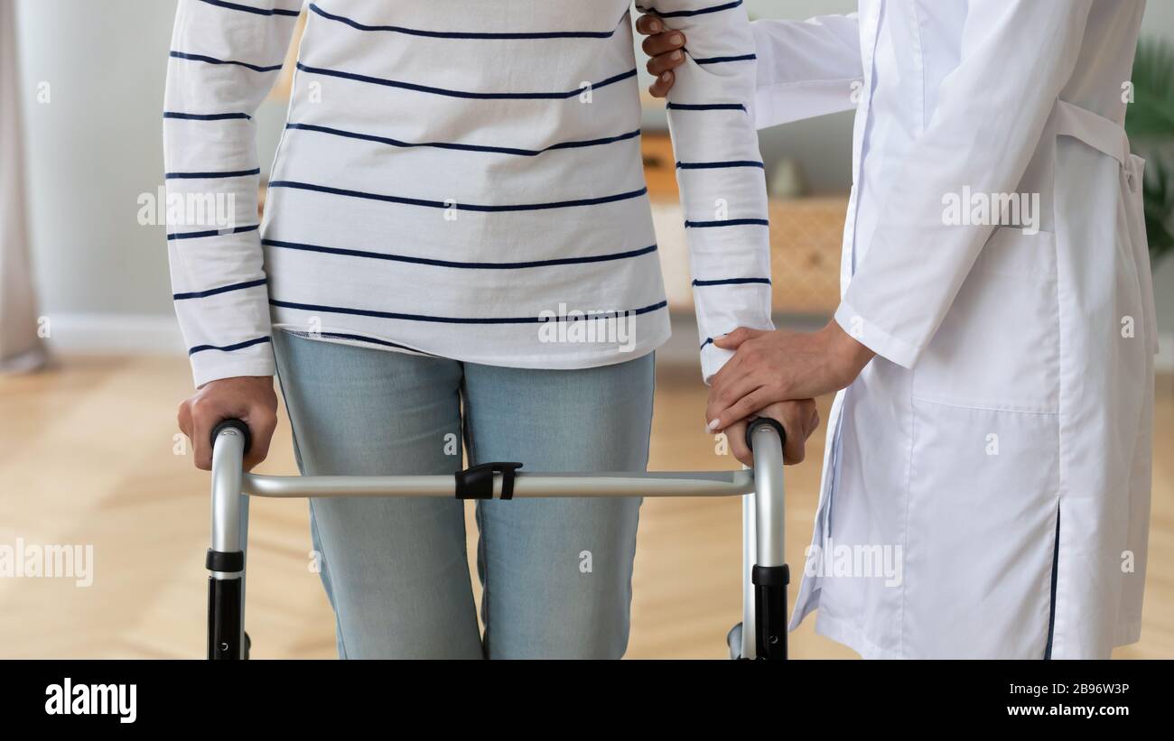 Infermiere di supporto aiuto disabili vecchia signora con camminatore Foto Stock