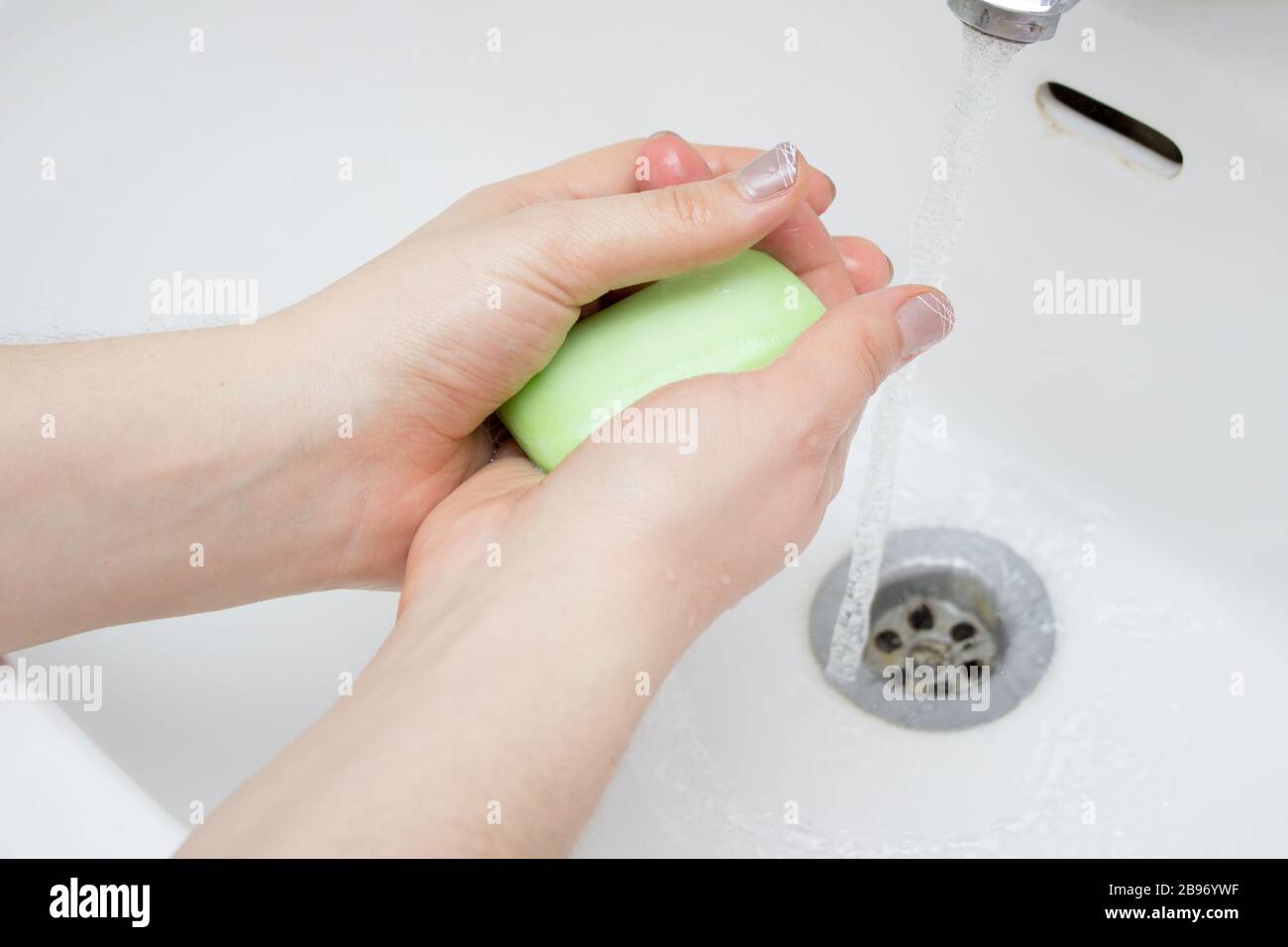 Donna usa il sapone e lavando le mani sotto il rubinetto dell'acqua. Dettagli della mano sul concetto di igiene. Foto Stock