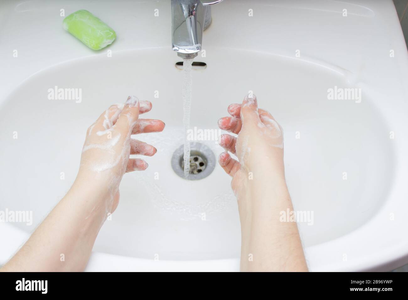 Concetto di igiene. Lavare le mani con acqua e sapone sotto il rubinetto Foto Stock