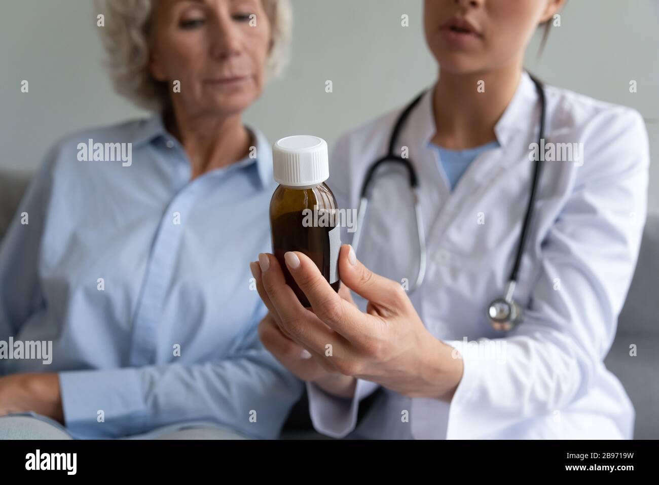 Medico giovane donna prescrive il medicinale al paziente anziano Foto Stock