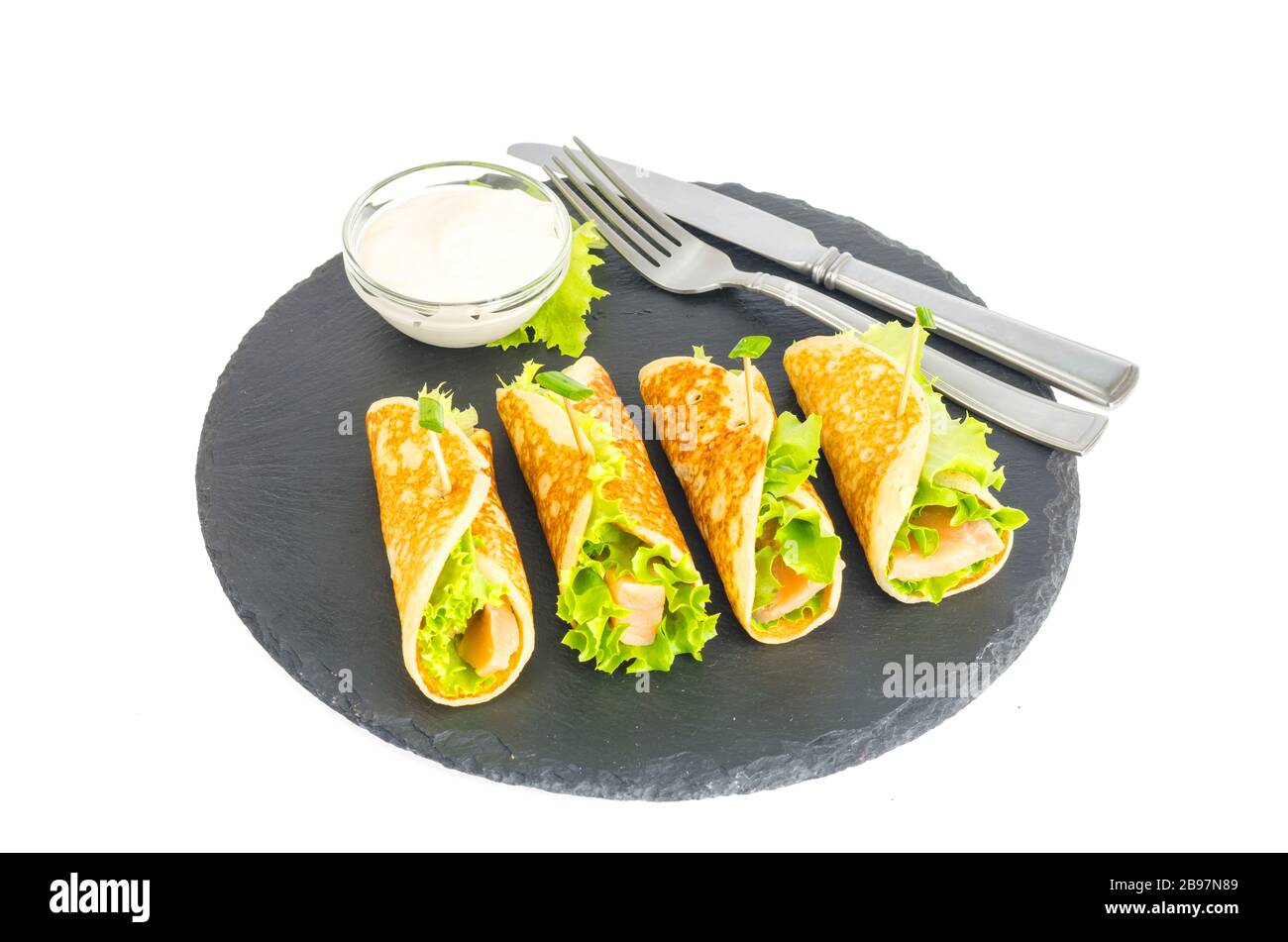 Involtini di pancake con pesce e lattuga. Pane al salmone con formaggio. Sulla piastra di pietra nera. Foto studio Foto Stock