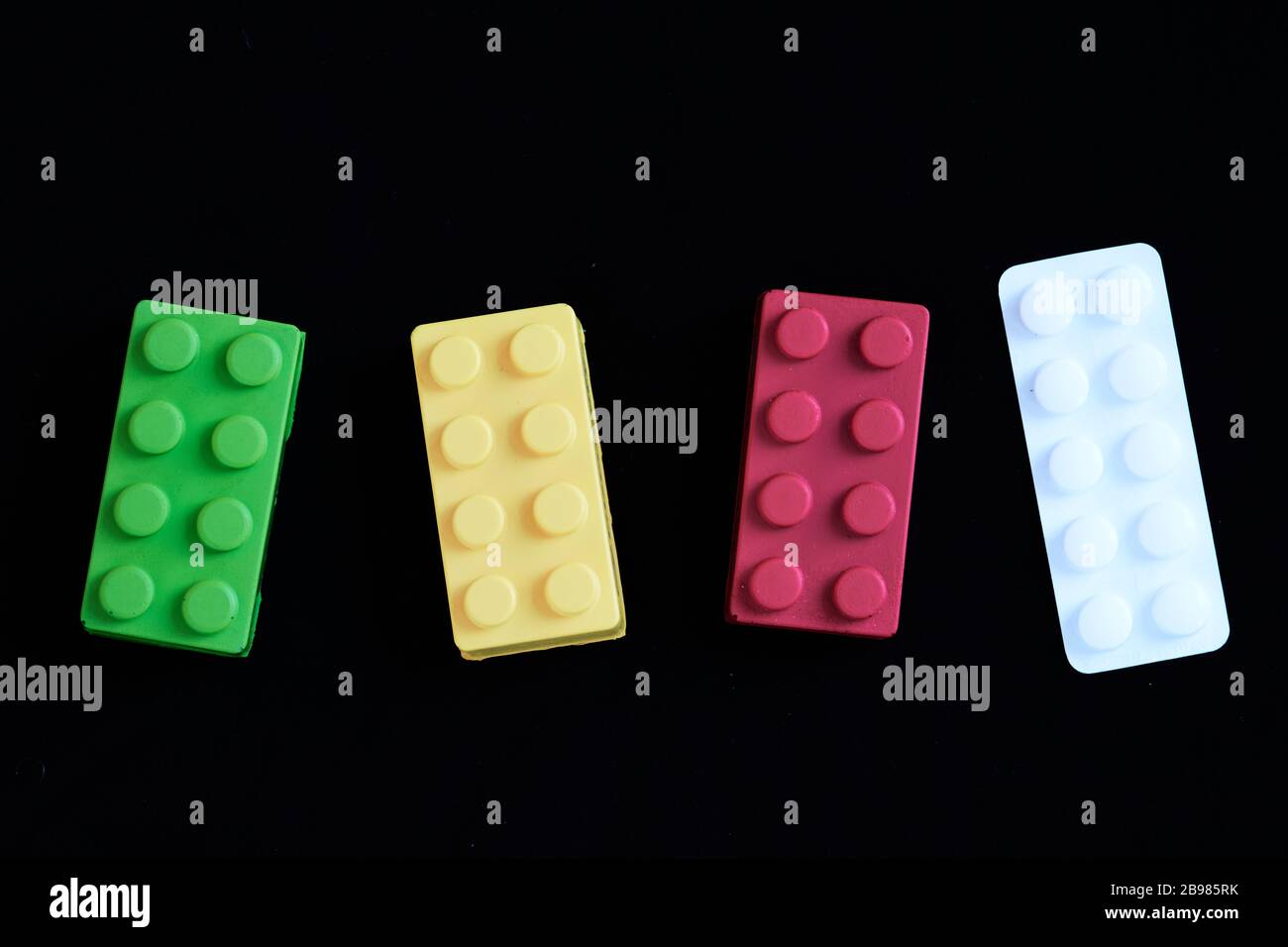 Giocattoli verdi, gialli e rossi allineati come semaforo con una tavoletta di paracetamolo bianco. Concetto di stato di allerta per Coronavirus covid-19, sistema sanitario critico Foto Stock