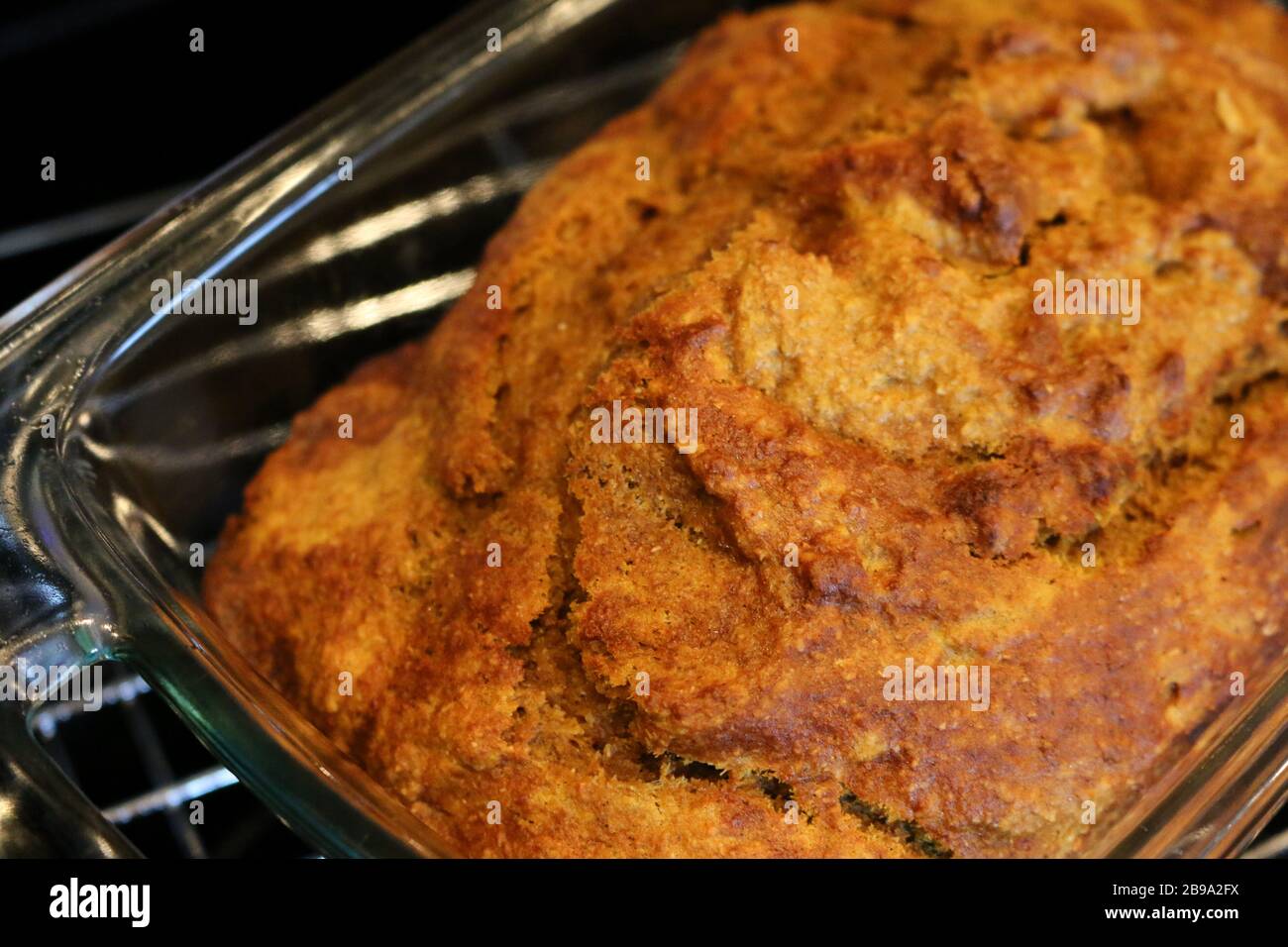 Primo piano del pane di zucca fresco fatto in casa in una padella di vetro su una griglia di raffreddamento in metallo Foto Stock