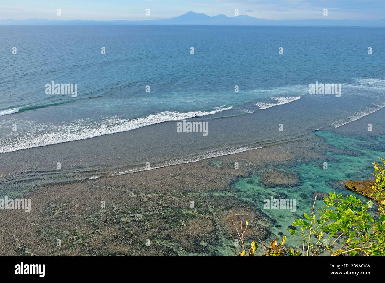 Bella costa con montagne vulcaniche sullo sfondo. Un luogo perfetto per surfisti in tutto il mondo a Uluwatu, Bali, Indonesia Foto Stock