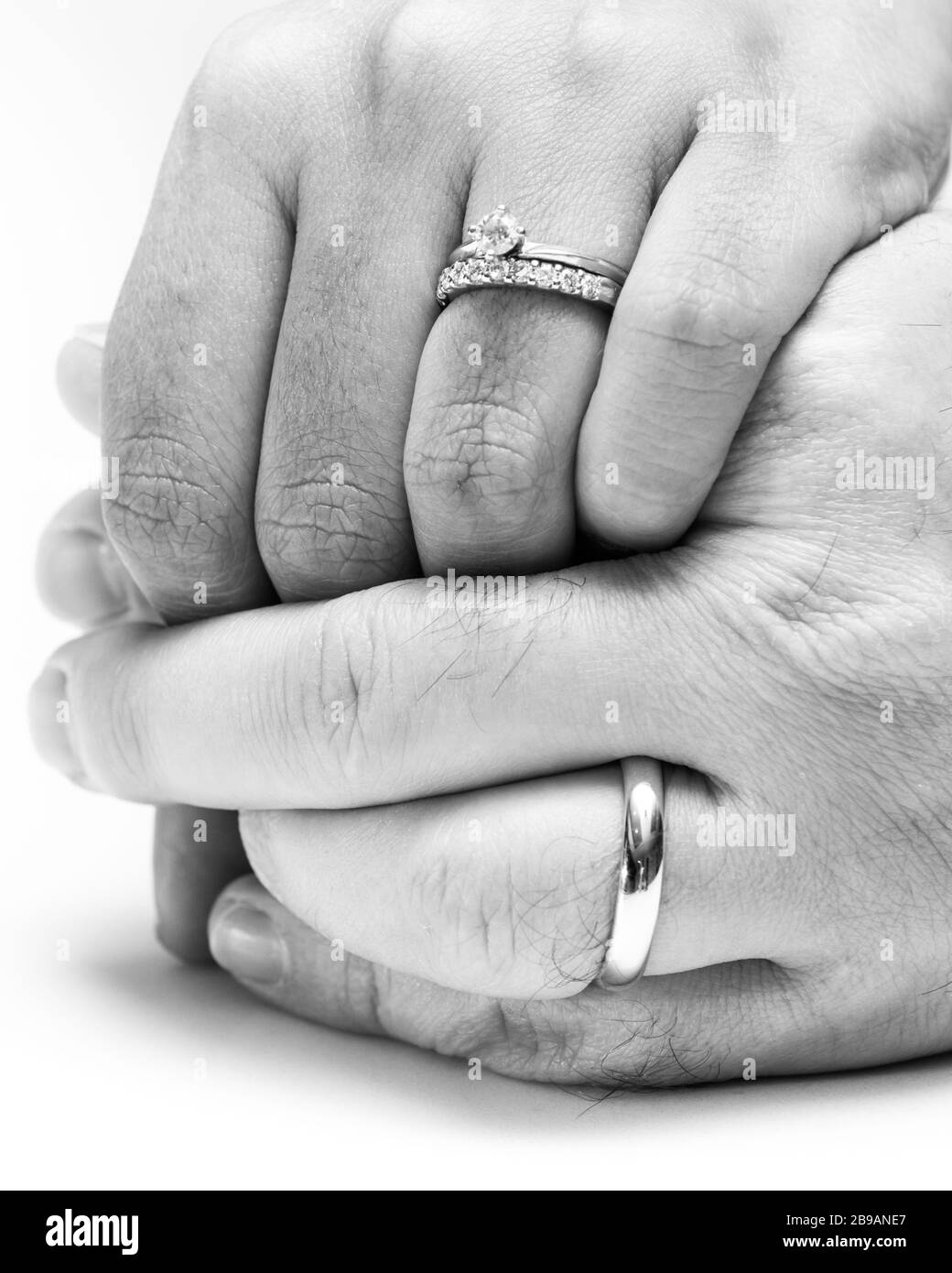 primo piano delle mani di una coppia che indossa le loro bande di nozze editate in bianco e nero per un effetto morbido Foto Stock
