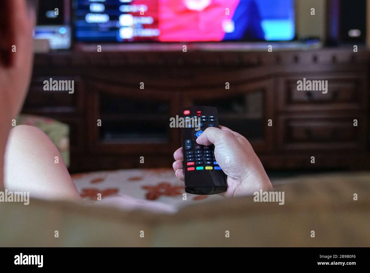 Uomo che guarda la tv con attenzione sulle mani sul telecomando. Home entertainment o concetto di soggiorno a casa. Foto Stock