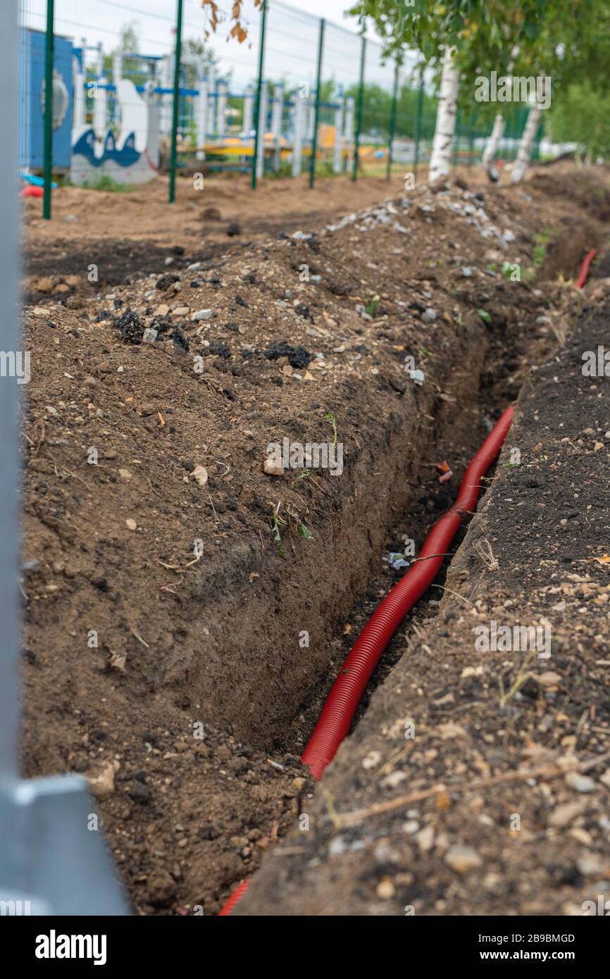 posa di cavi elettrici in trincea sotterranea. cavo in fibra ottica per internet veloce. Foto Stock