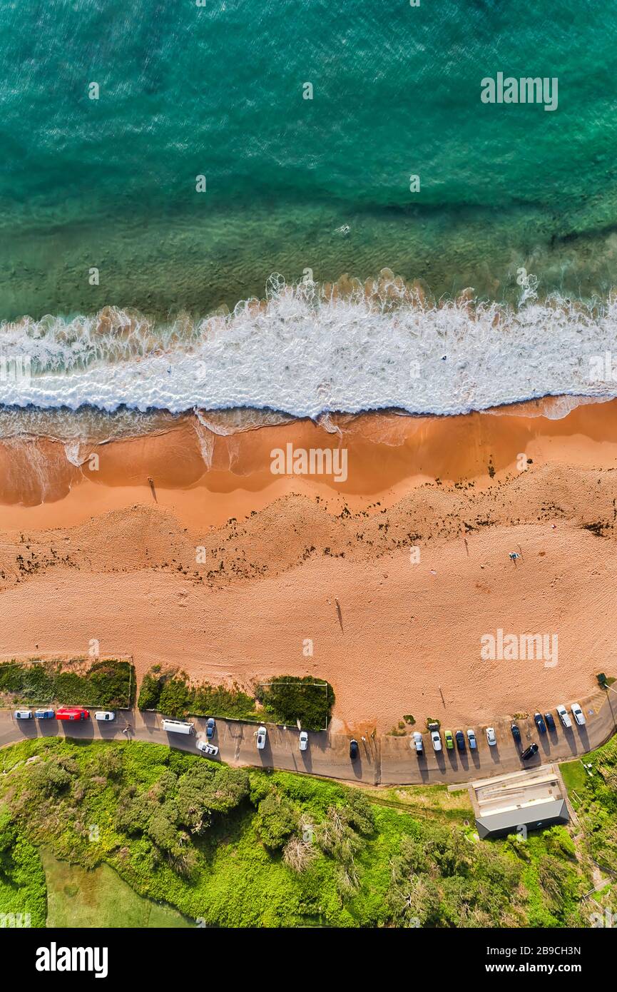 Sufers e nuotatori sulla spiaggia Warriewood delle spiagge del Nord di Sydney in una giornata di sole. Foto Stock