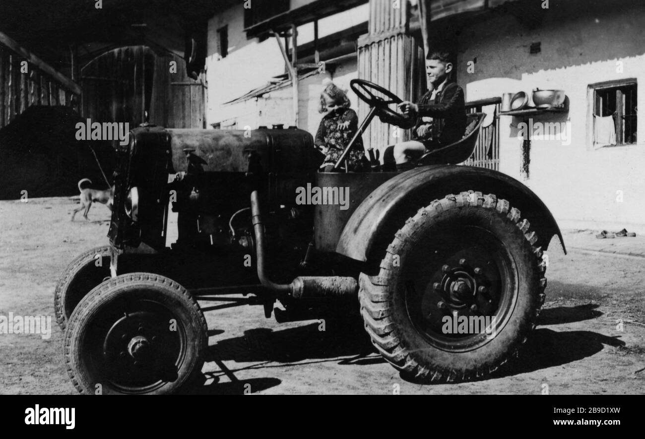 Un ragazzo gioca al volante di un trattore in una fattoria mentre sua  sorella lo guarda. [traduzione automatica] Foto stock - Alamy