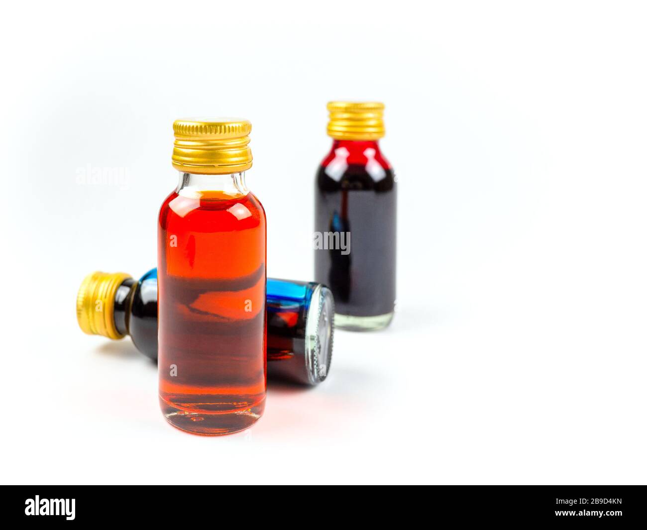 Colorazione alimentare in bottiglie di vetro su sfondo bianco isolato, giallo, blu, rosso, tre bottiglie di colorazione alimentare Foto Stock
