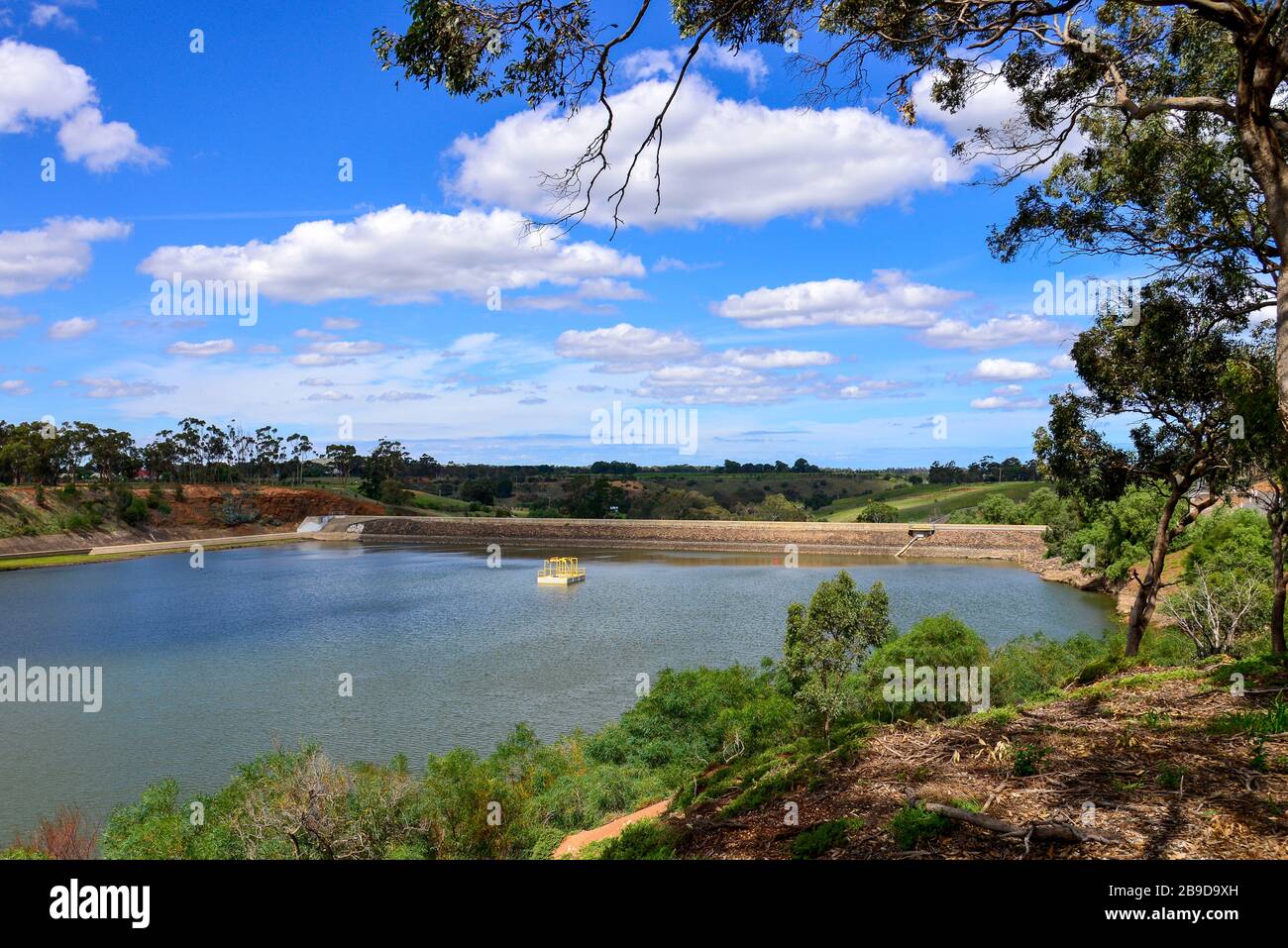 Werribee Weir Reservoir Water Storage bacino idrografico diga parete con alberi, nuvole e cielo blu Foto Stock