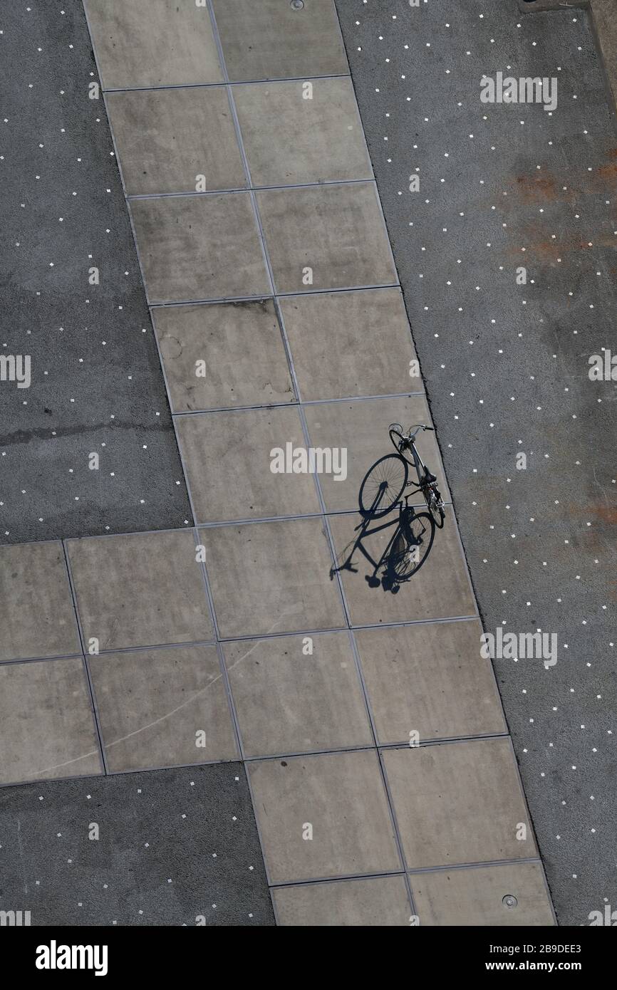 Vista dall'alto sul molo con una bicicletta solitaria che proietta lunghe ombre sull'interessante schema del molo in cemento Foto Stock