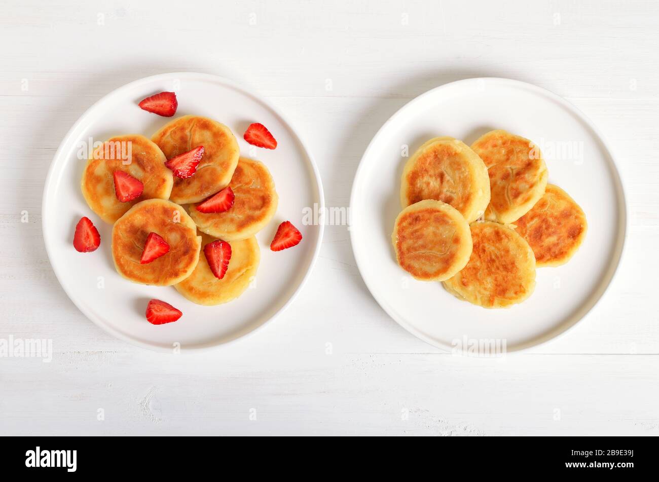 Pancake di formaggio casolare con fragola, sciroppi su sfondo bianco. Colazione tradizionale russa. Vista dall'alto, disposizione piatta Foto Stock