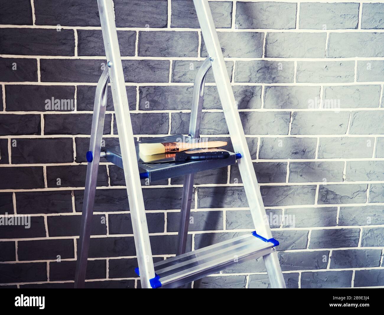 Lavori di rifinitura in una casa di nuova costruzione, scaletta e utensili decoratori vicino a muro riparazione attrezzi. Foto Stock