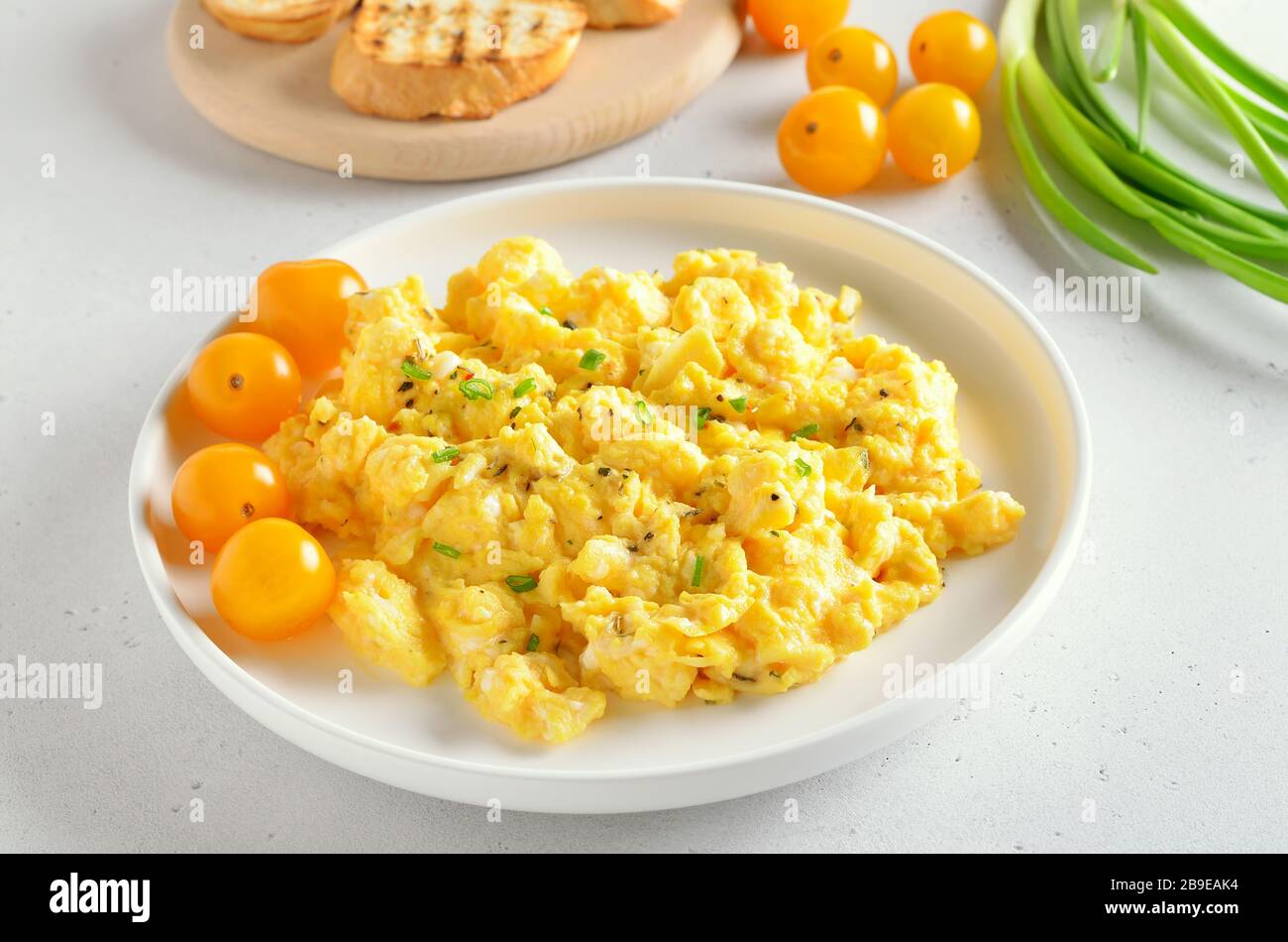 Uova strapazzate e pomodori sul piatto su sfondo di pietra bianca Foto Stock
