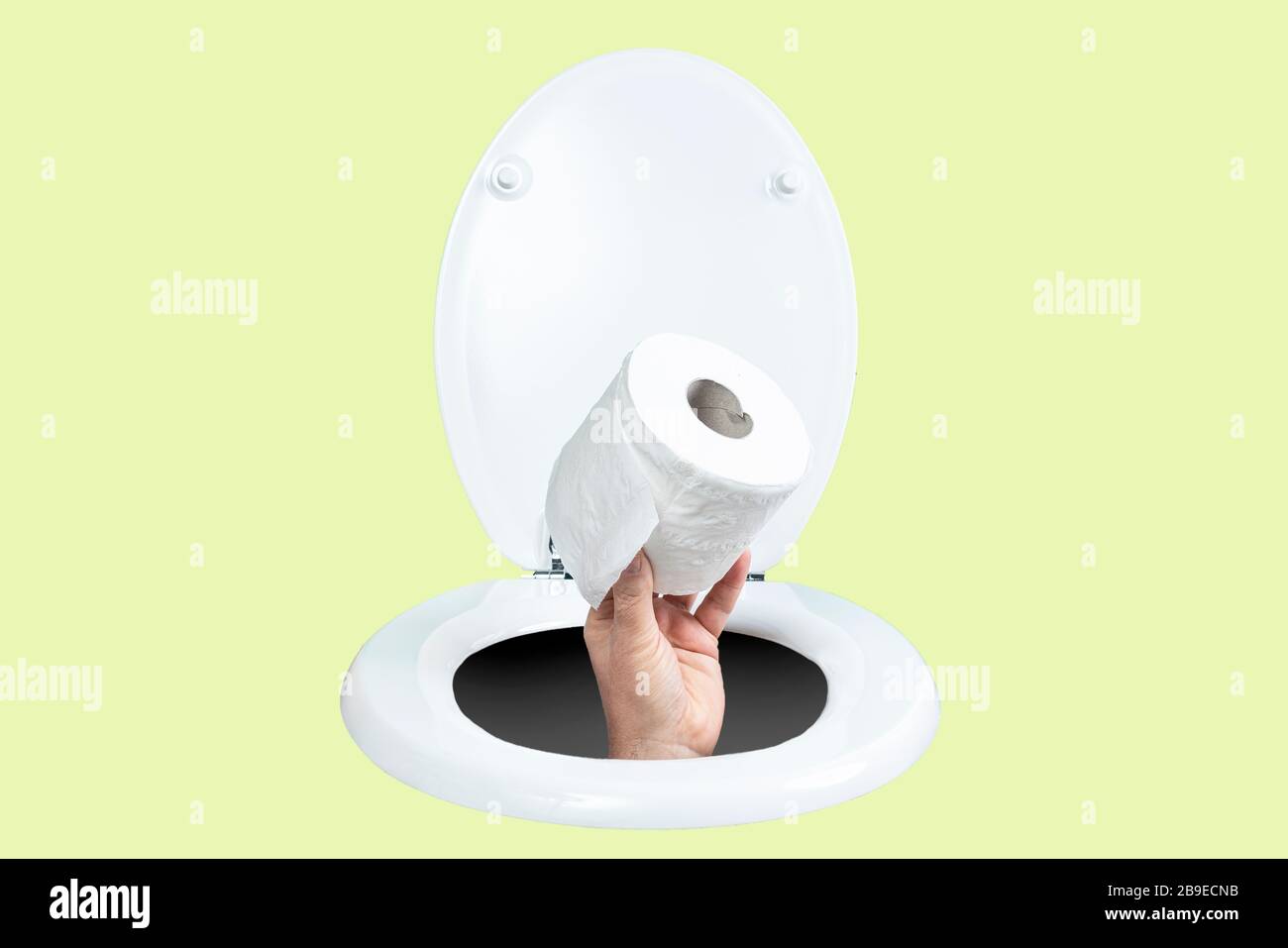 una mano con un rotolo di carta igienica che esce dalla toilette Foto Stock