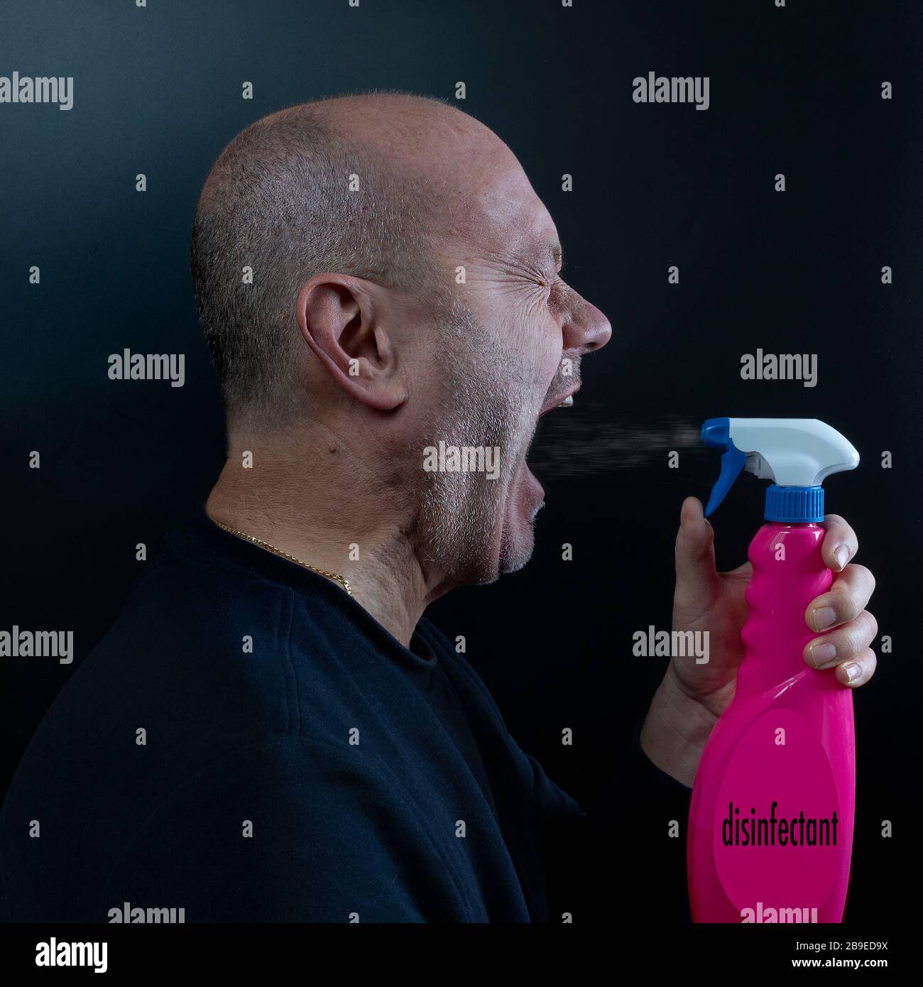 un uomo disinfetta la bocca con un flacone spray Foto Stock