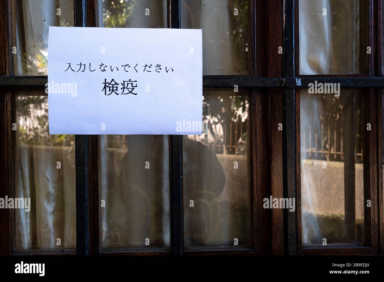 Un segno che dice non entrare, quarantena in lingua giapponese allegato a una finestra Foto Stock