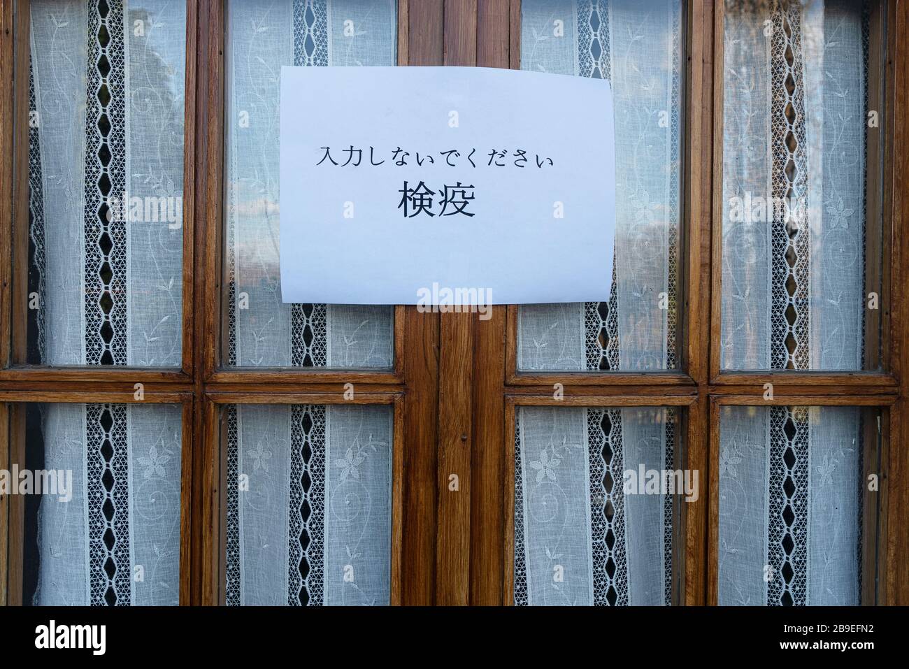 Un segno che dice non entrare, quarantena in lingua giapponese allegato a una finestra Foto Stock