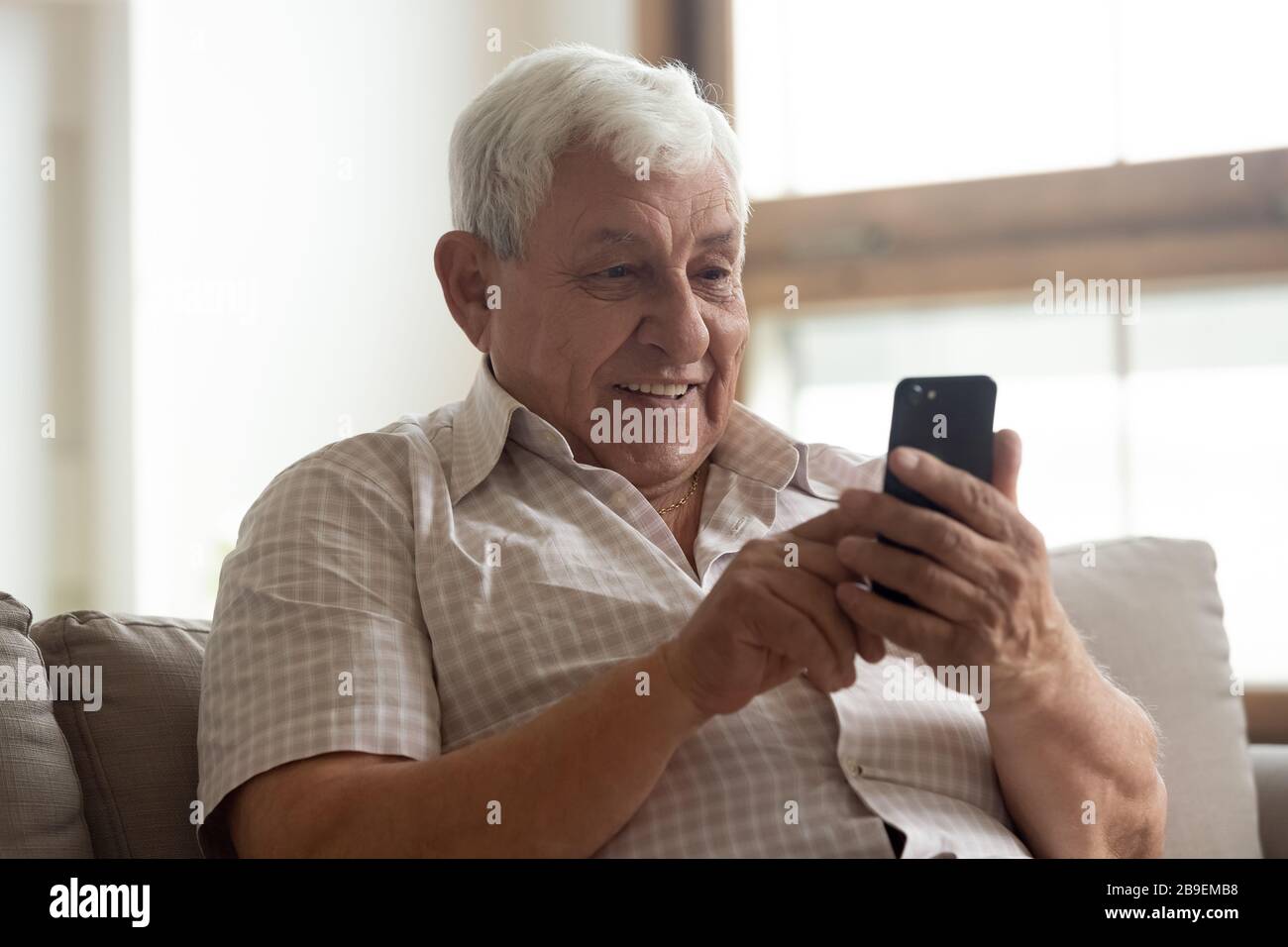 Sorridente uomo anziano che tiene il telefono, utilizzando le app per dispositivi mobili Foto Stock