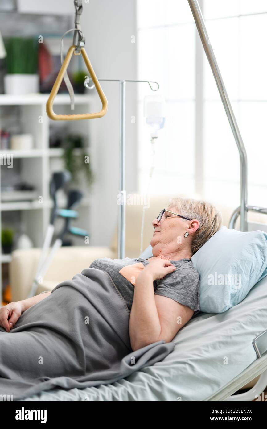 Vecchia donna caucasica in una casa di cura con problemi di salute che si posano sul letto. Foto Stock