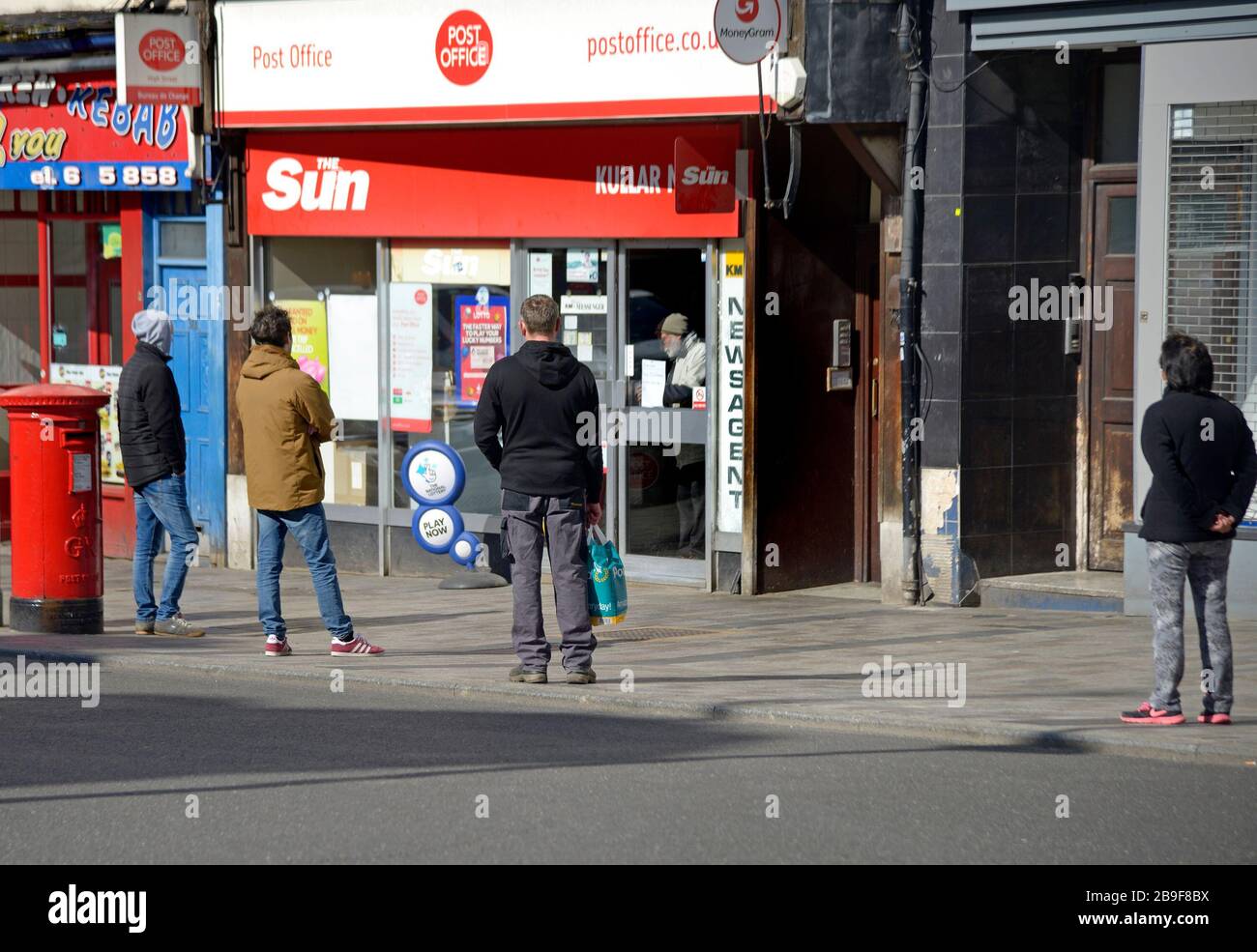 Maidstone, Kent, Regno Unito. 24 Marzo 2020. Le persone mostrano un'allontanamento sociale mentre si accodano fuori da un ufficio postale prima di essere lasciate in uno alla volta Foto Stock