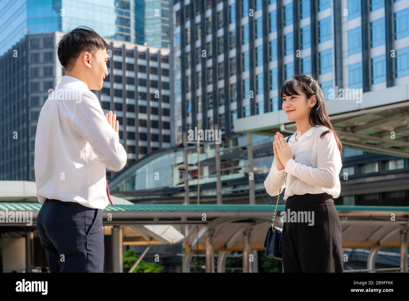 Il rispetto di paga è nuovo saluto del romanzo per evitare la diffusione del coronavirus. Due giovani uomini d'affari asiatici e uomini d'affari amici si incontrano in font di bui ufficio Foto Stock