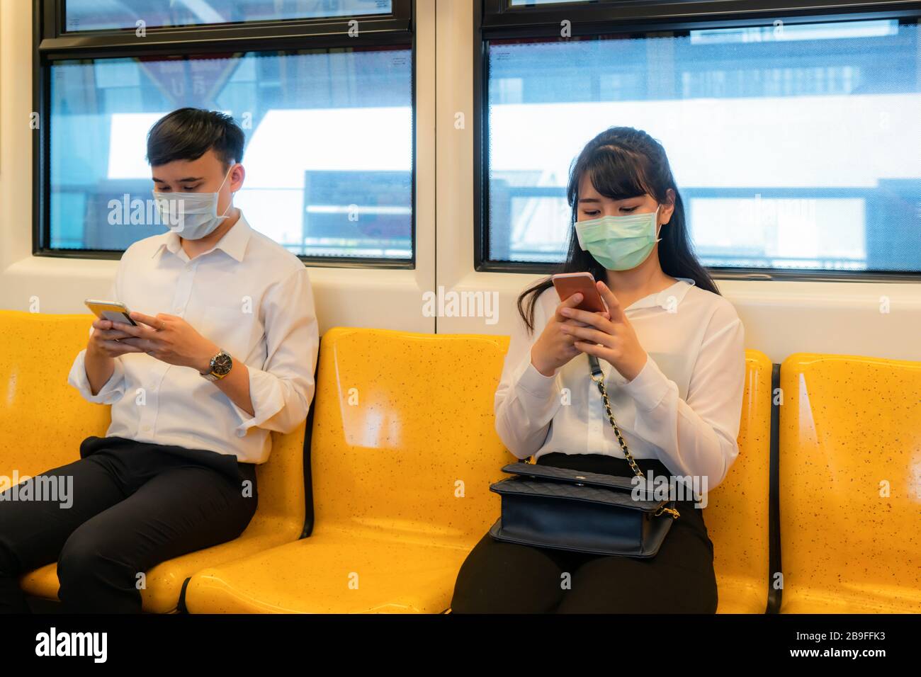 Due persone asiatiche che indossano la maschera seduto a distanza della metropolitana per un posto da altre persone mantenere la distanza di protezione dai virus COVID-19 e la gente sociale Foto Stock