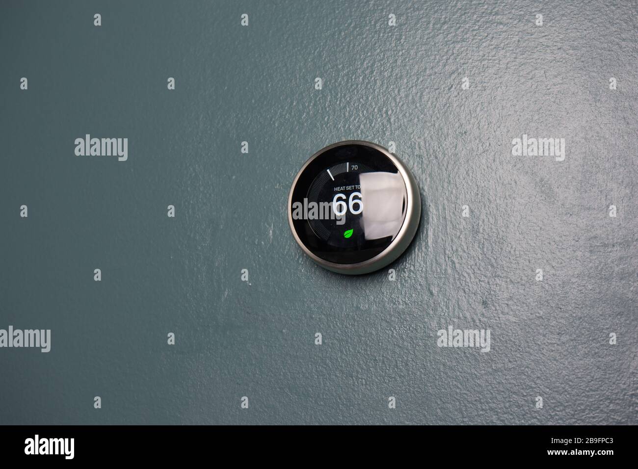 Termostato intelligente a casa con visualizzazione a 66 gradi. Regolazione della temperatura del termostato sulla parete blu per risparmiare denaro con Green TECH. Foto Stock