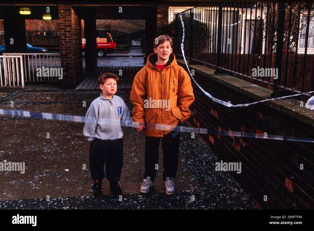 I bambini locali storditi stanno da una linea di polizia il giorno dopo che l'IRA detonò una potente bomba camion in South Quay, Londra Docklands il 9 febbraio 1996, l'uccisione due & causando £150 milioni di danni. Foto Stock