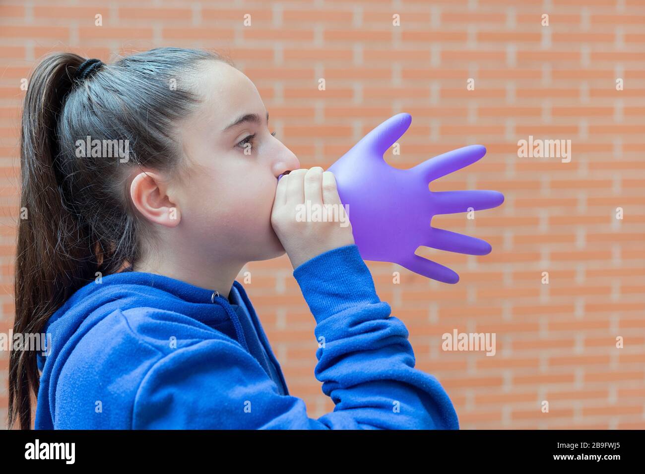 ragazza gonfiare un guanto di lattice. concetto di gioco, salute, gioia Foto Stock