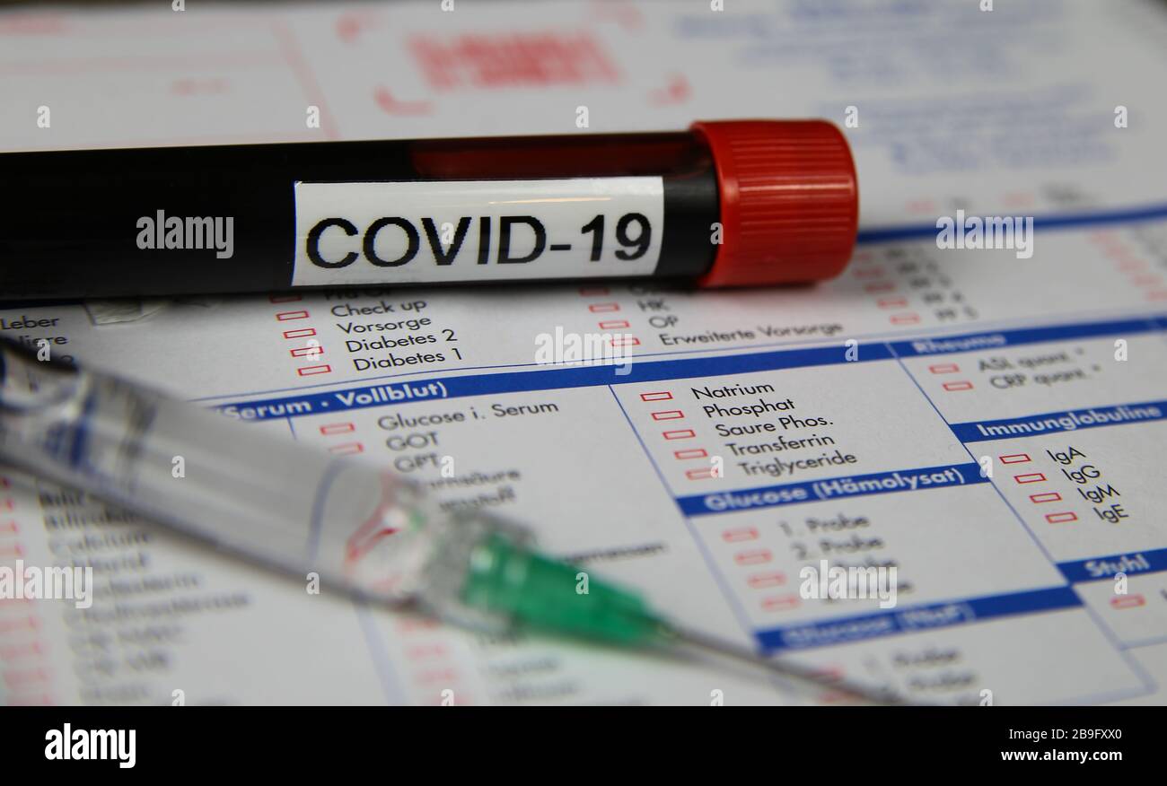 Viersen, Germania - Marzo 22. 2020: Primo piano della provetta per campioni di sangue isolata con Word covid-19 e siringa per iniezione. Modulo di richiesta di test di laboratorio sfocato Foto Stock