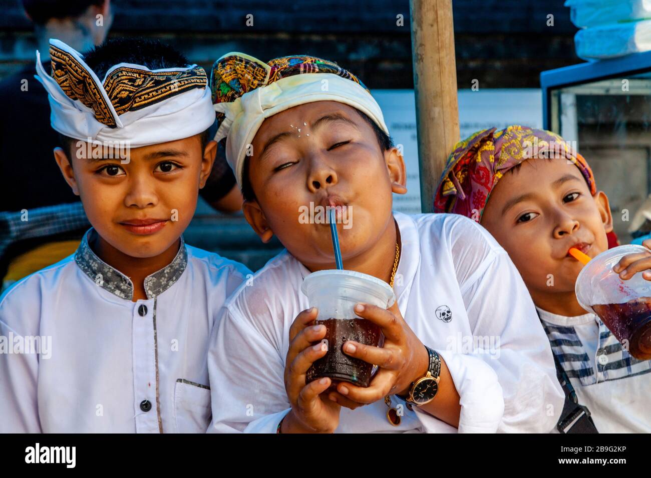 Un gruppo di bambini indù Balinesi che bevono bibite analcoliche durante UN Festival religioso locale, Ubud, Bali, Indonesia. Foto Stock