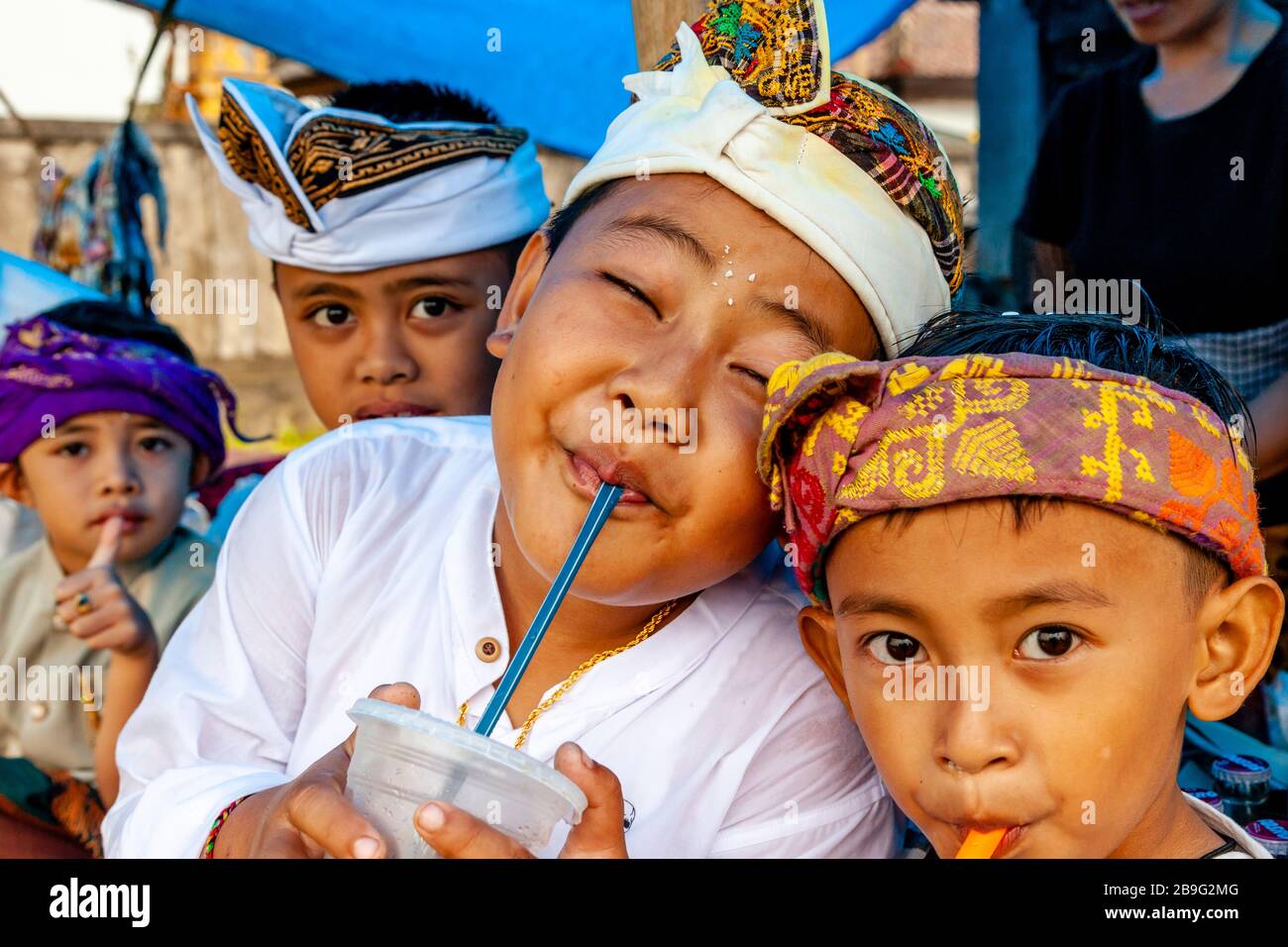 Un gruppo di bambini indù Balinesi che bevono bibite analcoliche durante UN Festival religioso locale, Ubud, Bali, Indonesia. Foto Stock