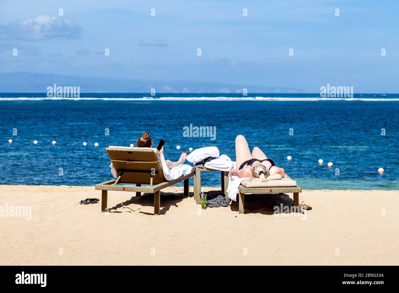 Due visitatori possono prendere il sole sulla spiaggia, Sanur Beach, Sanur, Bali, Indonesia. Foto Stock