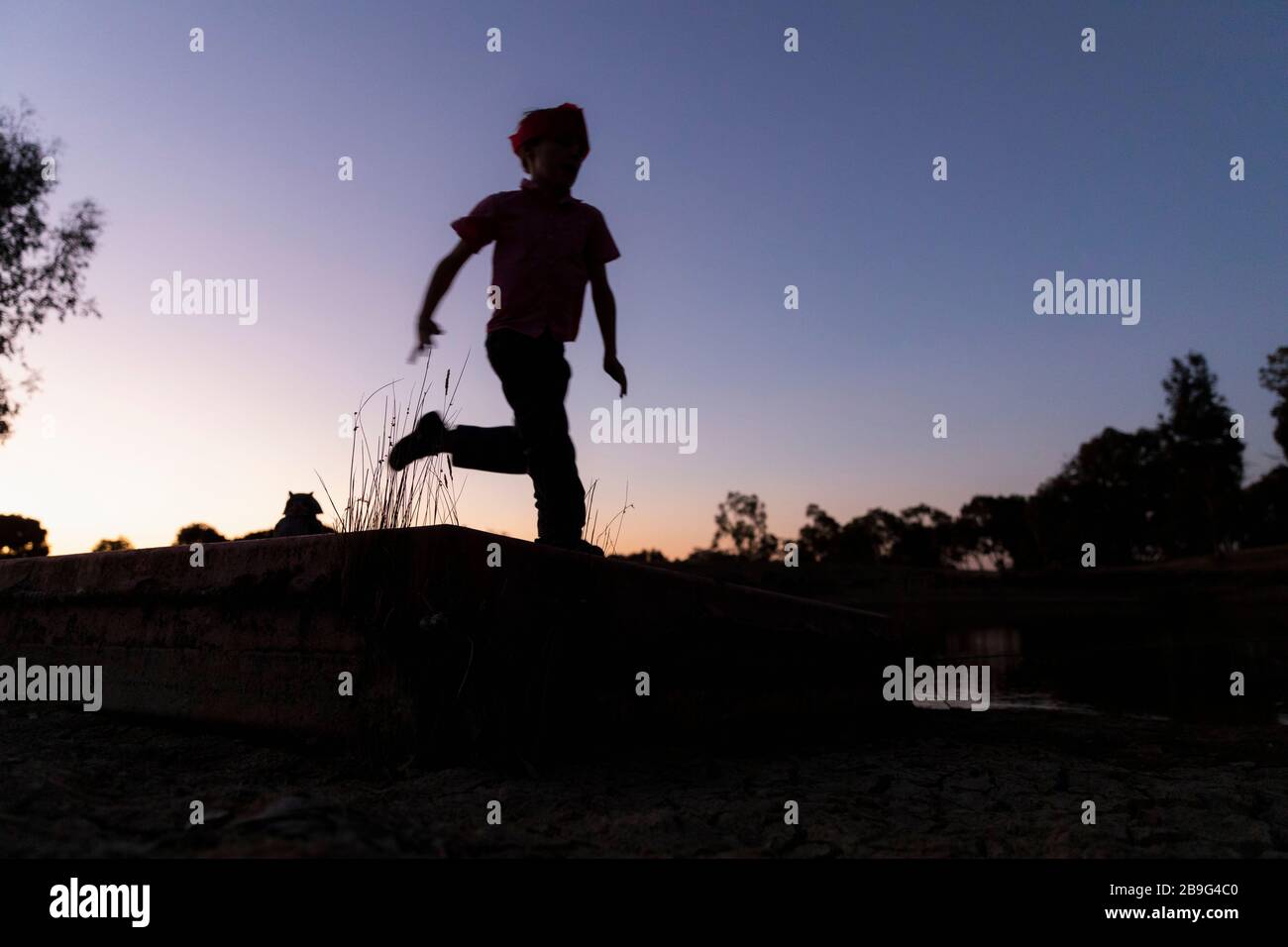 Ragazzo silhouette che corre contro il cielo crepuscolo Foto Stock