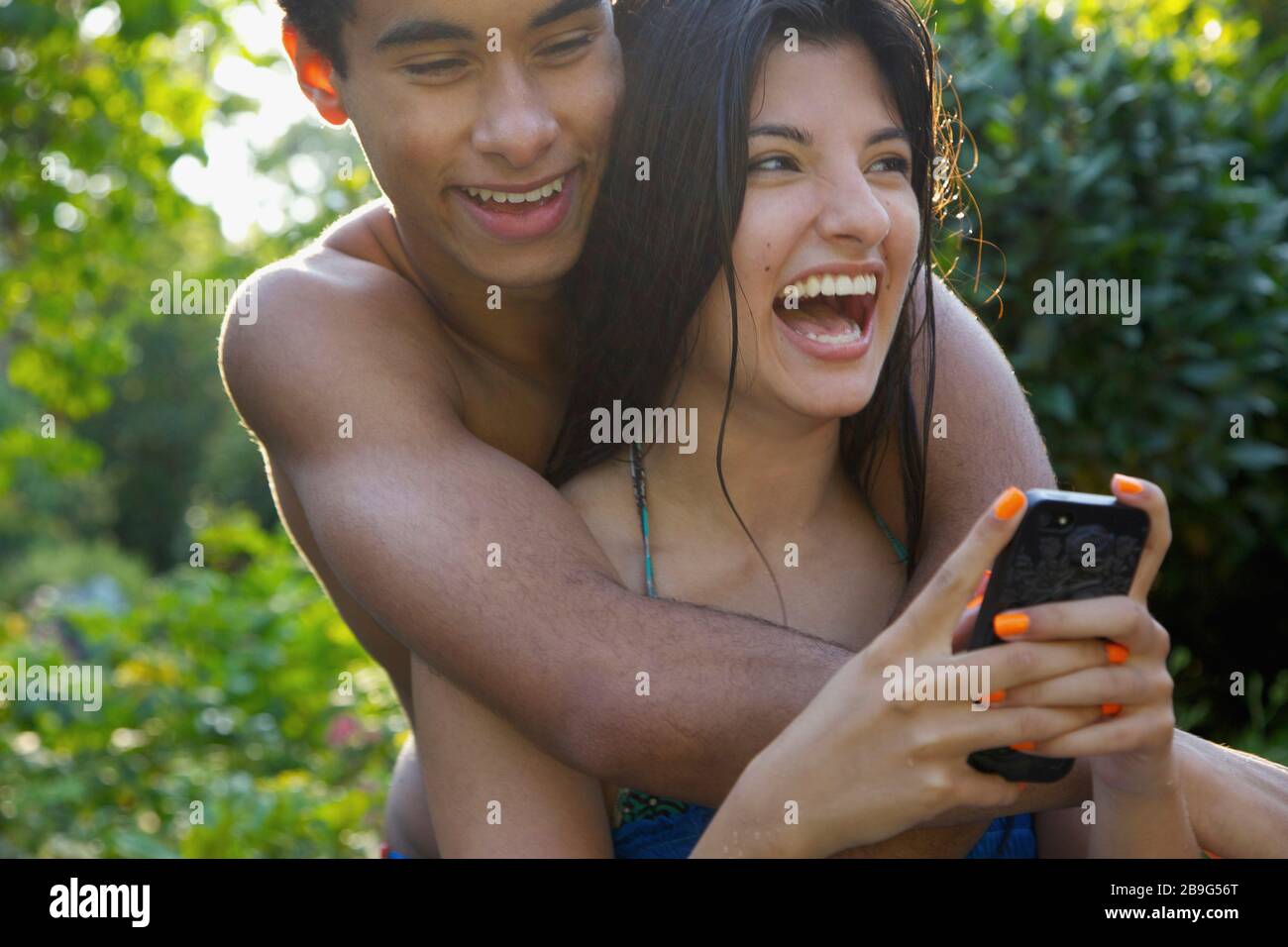 Felice, affettuosa giovane coppia utilizzando smartphone sul patio estivo Foto Stock