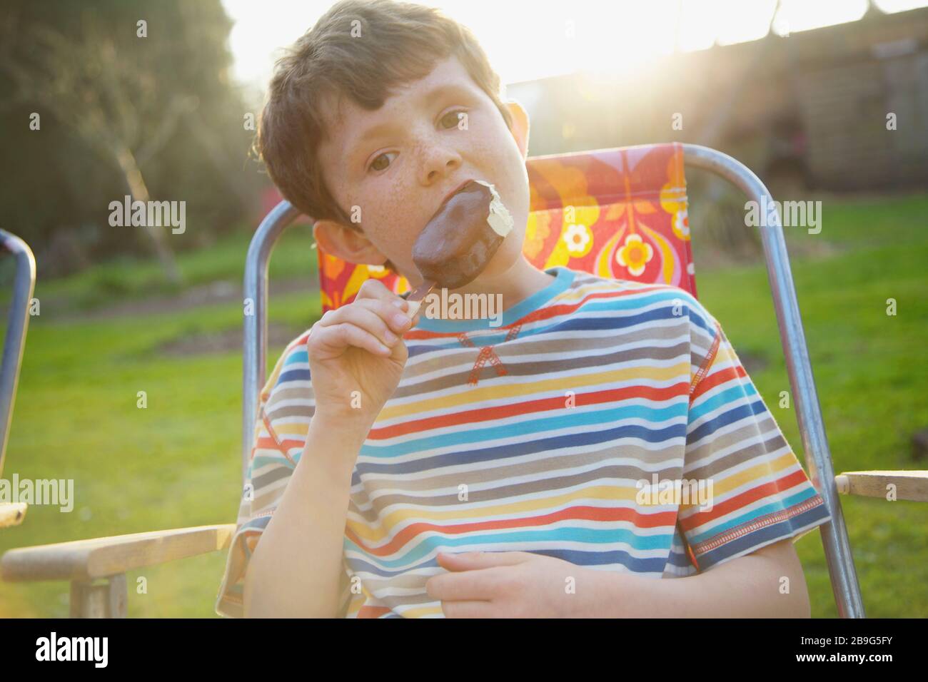 Portrait boy mangiare cioccolato gelato bar sul patio estivo Foto Stock