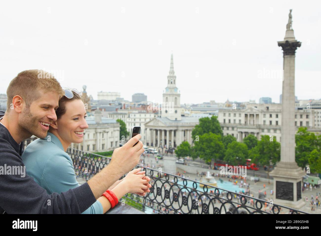 Buona coppia con la macchina fotografica sopra Trafalgar Square, Londra, Regno Unito Foto Stock