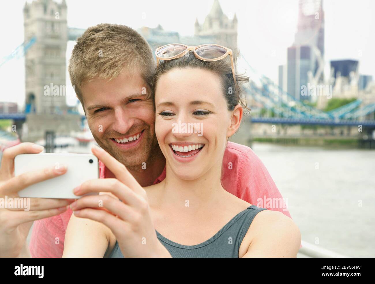 Buona coppia che prende selfie con la fotocamera del telefono di fronte a Tower Bridge, Londra, Regno Unito Foto Stock