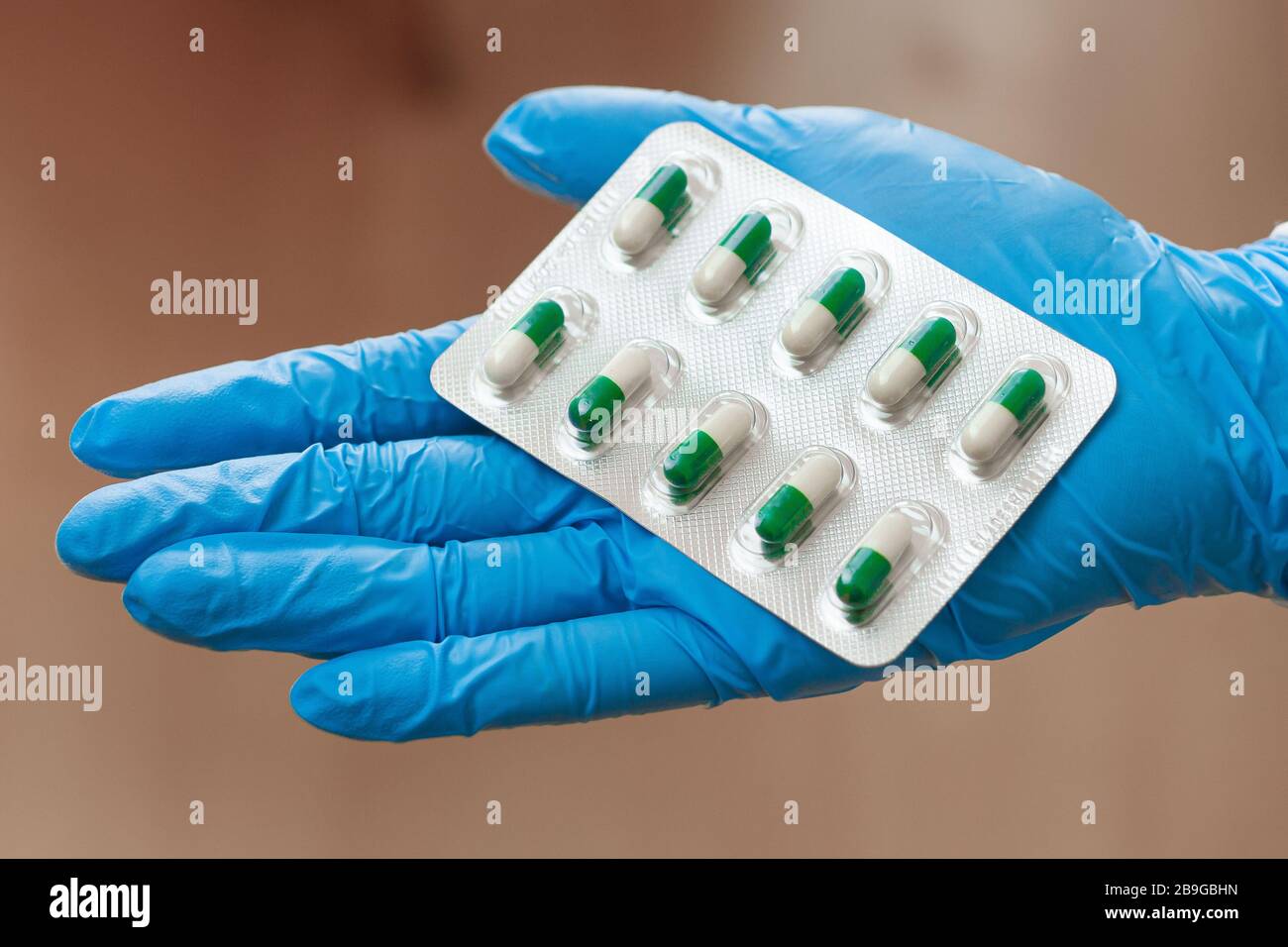 Pillole in mano donna in guanti blu. Vitamine o medicinali per il trattamento del coronavirus. Foto Stock