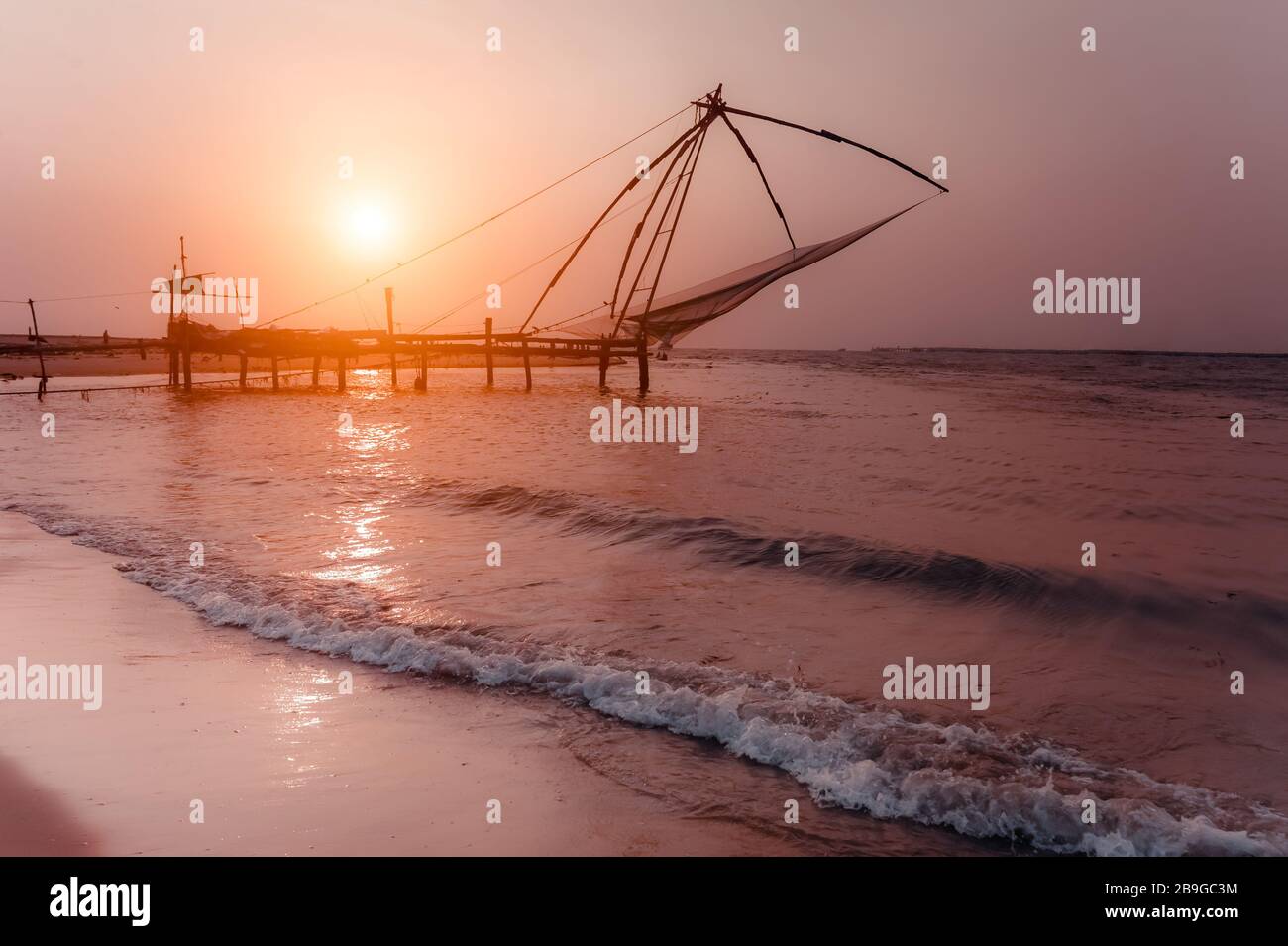 Tramonto sulla spiaggia tropicale. Paesaggio della costa dell'oceano con la silhouette cinese delle reti da pesca a Cochin (Kochi). India meridionale, Kerala, Kochin Foto Stock