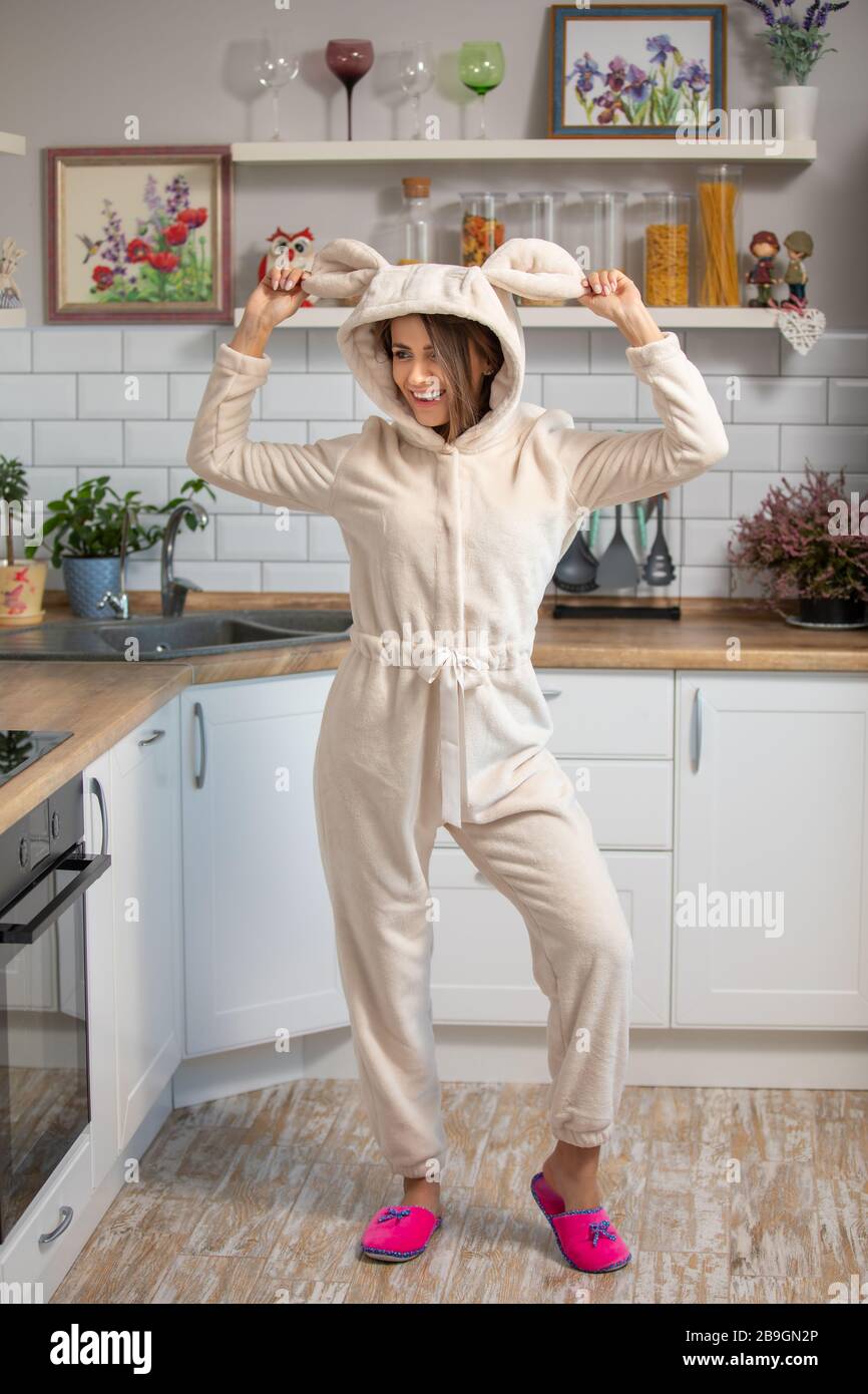 bella giovane donna brunetta in soffice pigiama su una cucina scandinava bianca Foto Stock