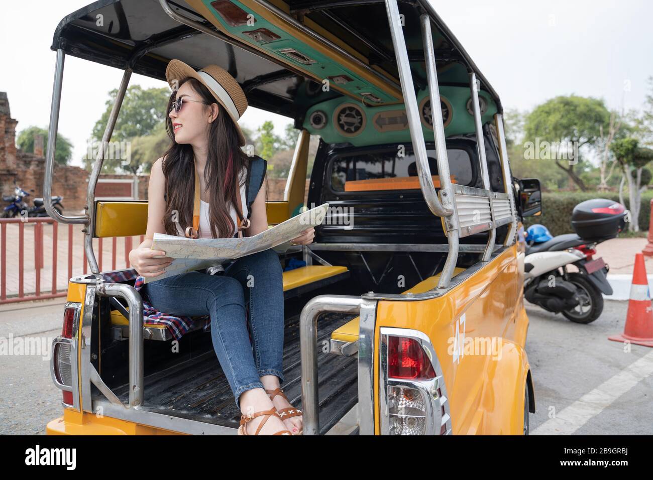 Una donna turistica asiatica che guarda una mappa in un tuk-tuk mentre viaggi in Ayutthaya, Thailandia. Foto Stock