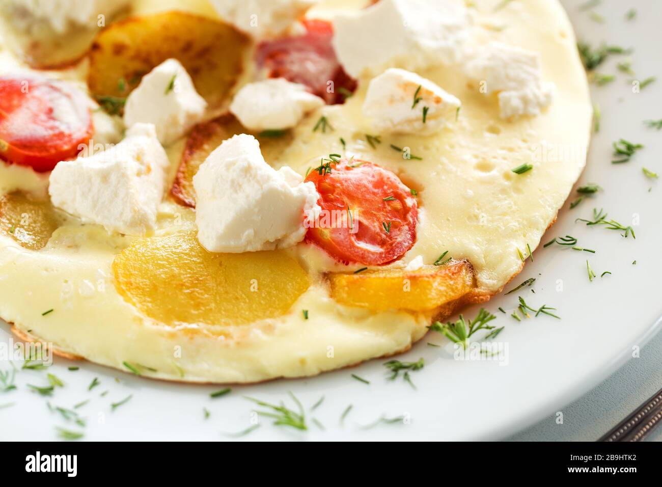 Deliziosa frittata con pomodoro, patate e capra o formaggio greco feta Foto Stock