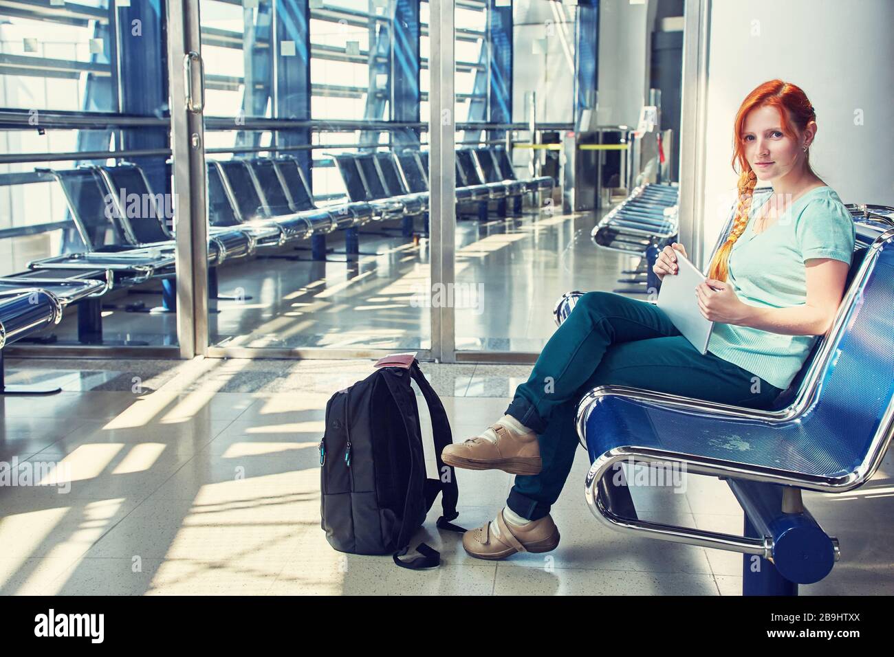 Donna in aeroporto. redhead ragazza con computer tablet. Affari e viaggi Foto Stock