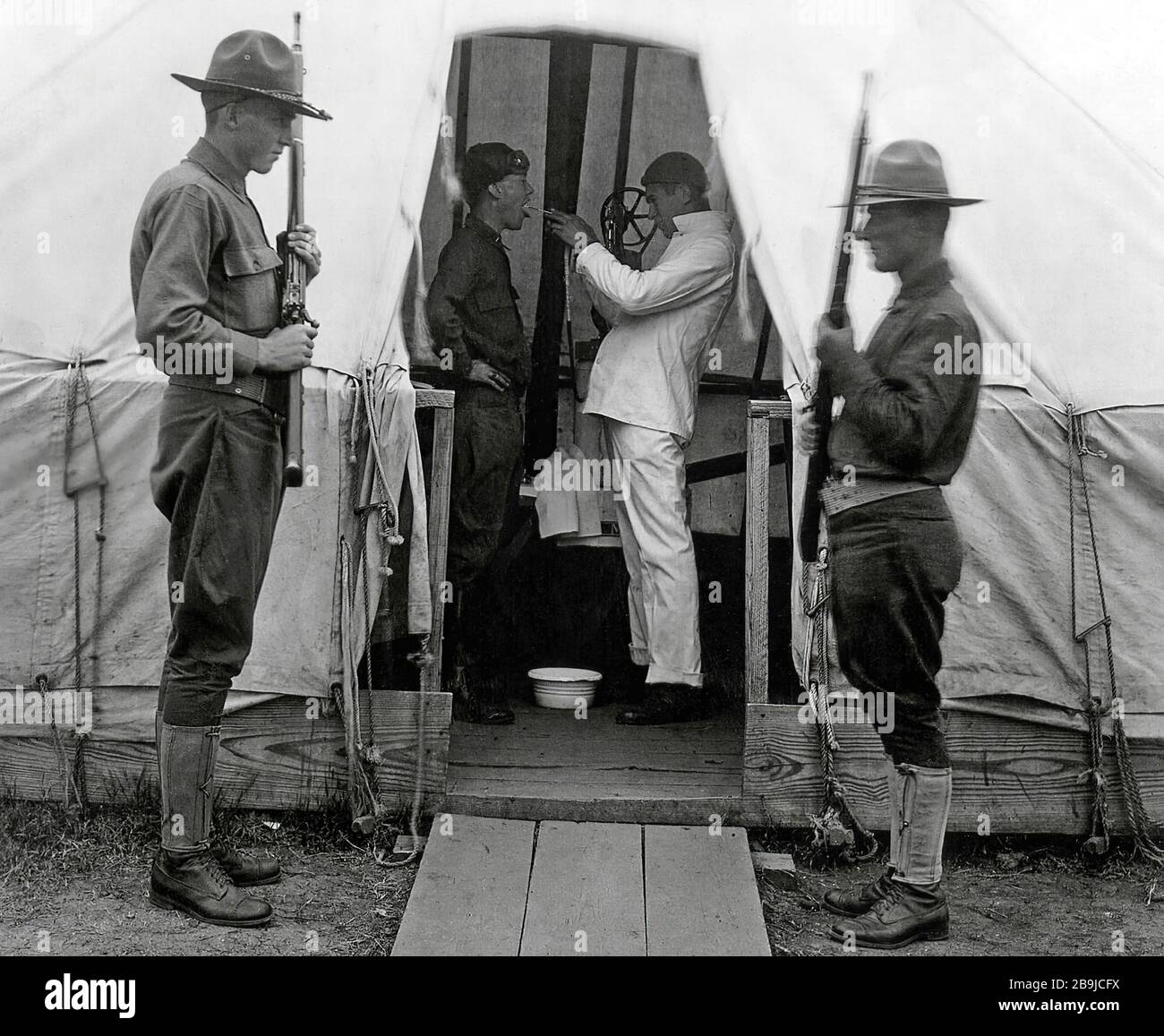 Il soldato americano ottiene la gola spruzzata per prevenire l'influenza. Dicembre 1918. Tenda medica a Love Field, Dallas, Texas, durante la pandemia influenzale 'Panish' del 1918-19. 1918-1919. Un'epidemia di 'influenza Panish' si diffuse in tutto il mondo. Sono morti almeno 20 milioni, anche se secondo alcune stime il pedaggio finale è stato di 50 milioni. Foto Stock