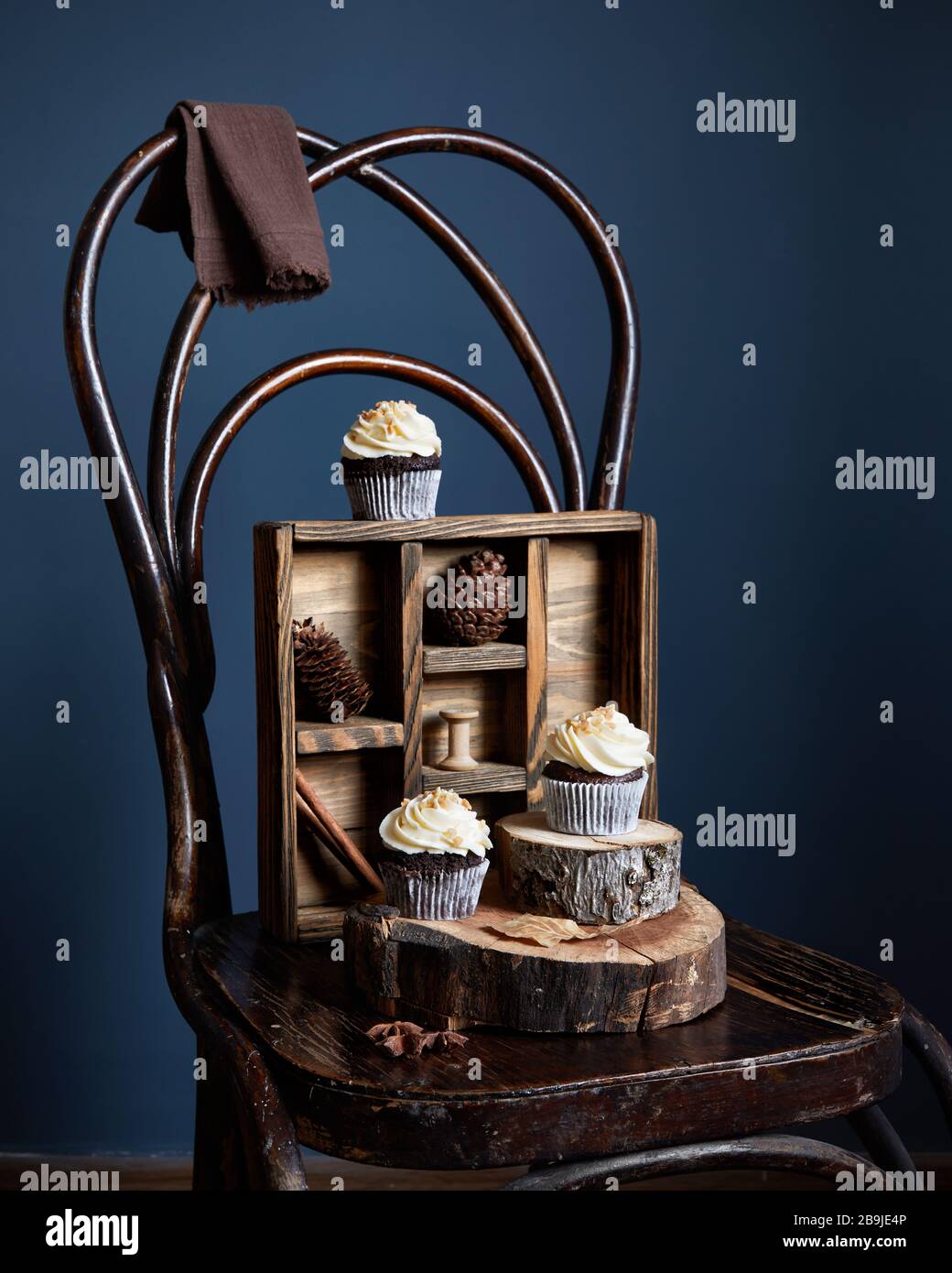 Cupcake al cioccolato decorati con crema di burro bianco e arachidi su vecchia sedia vintage su sfondo scuro. Spazio libero per il testo Foto Stock