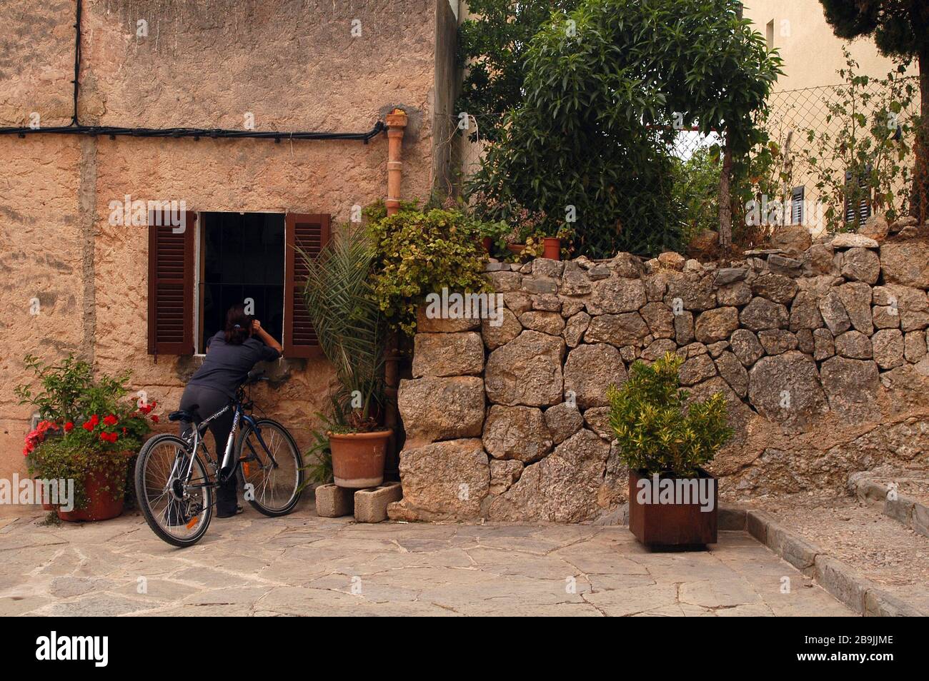 Donna con bici si appoggia attraverso una finestra di casa in spagna. Foto Stock